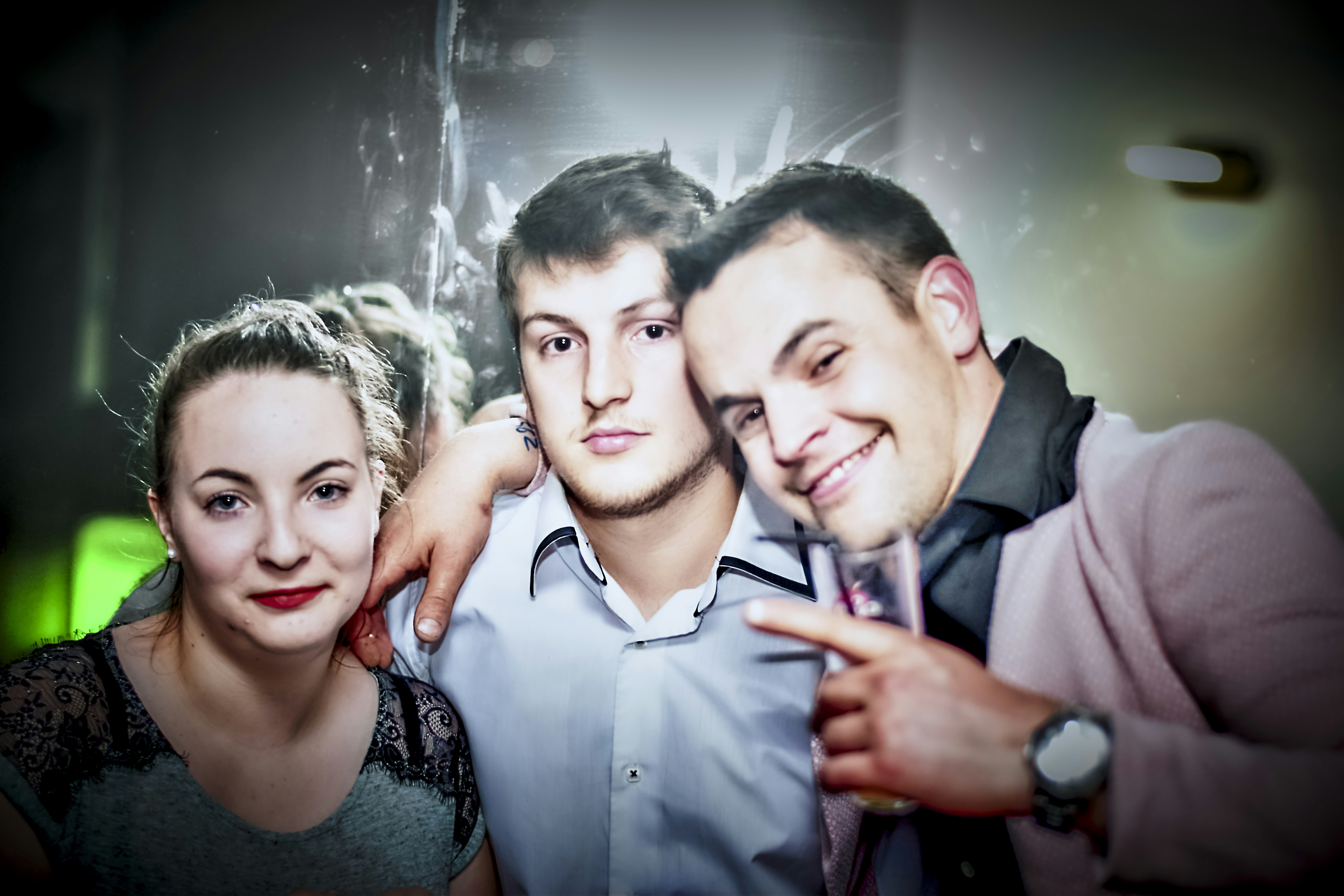 Three friends posing for a picture at a party.