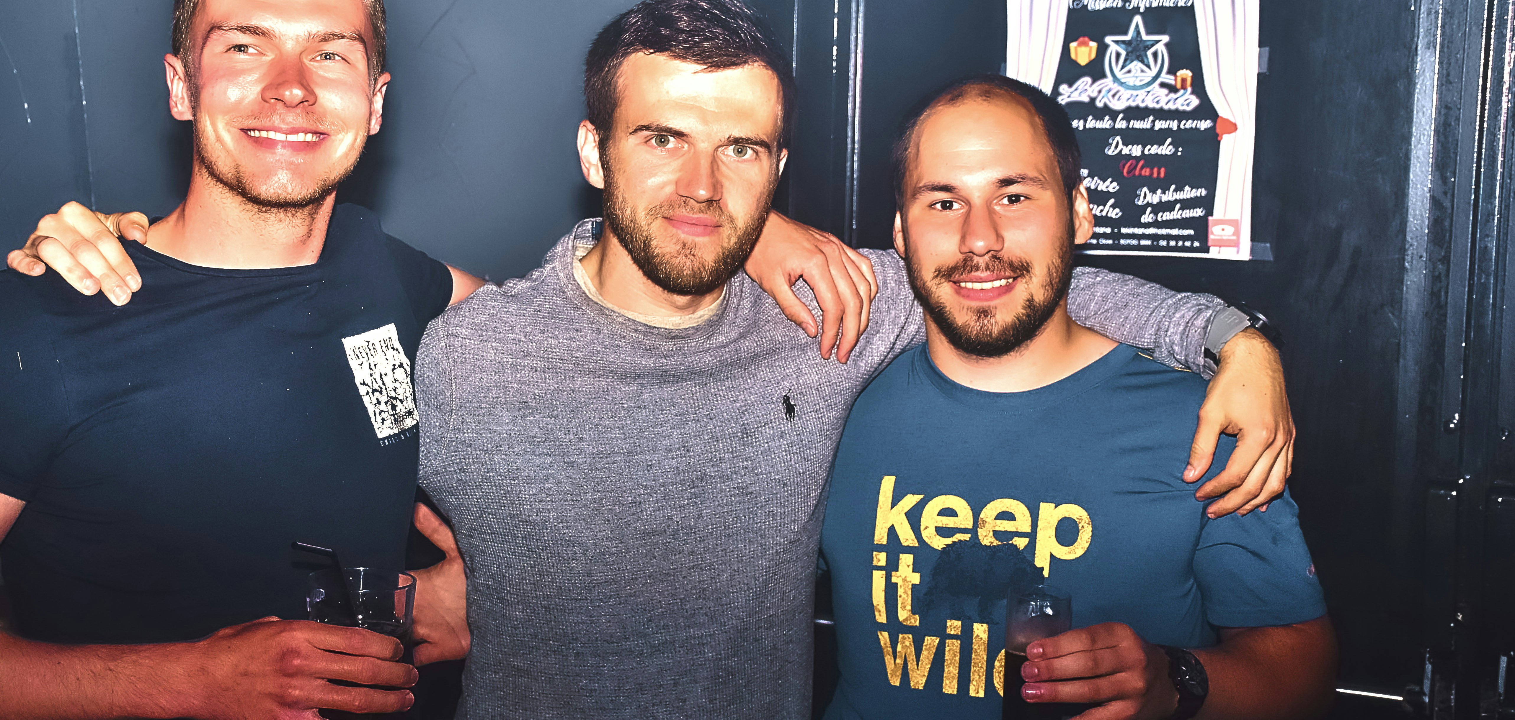 Three men smiling with arms around each other.