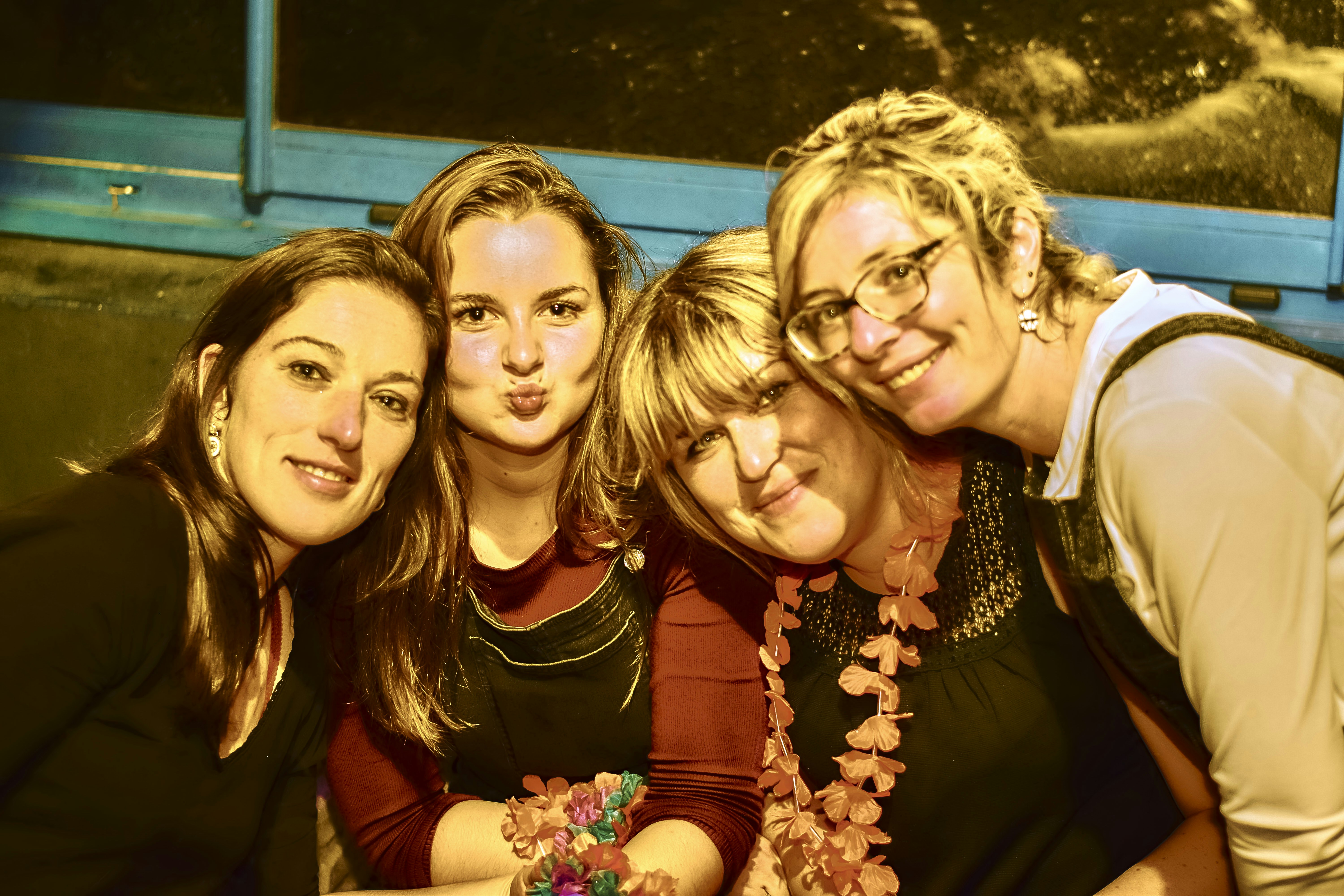 Four women smiling and posing for a group selfie