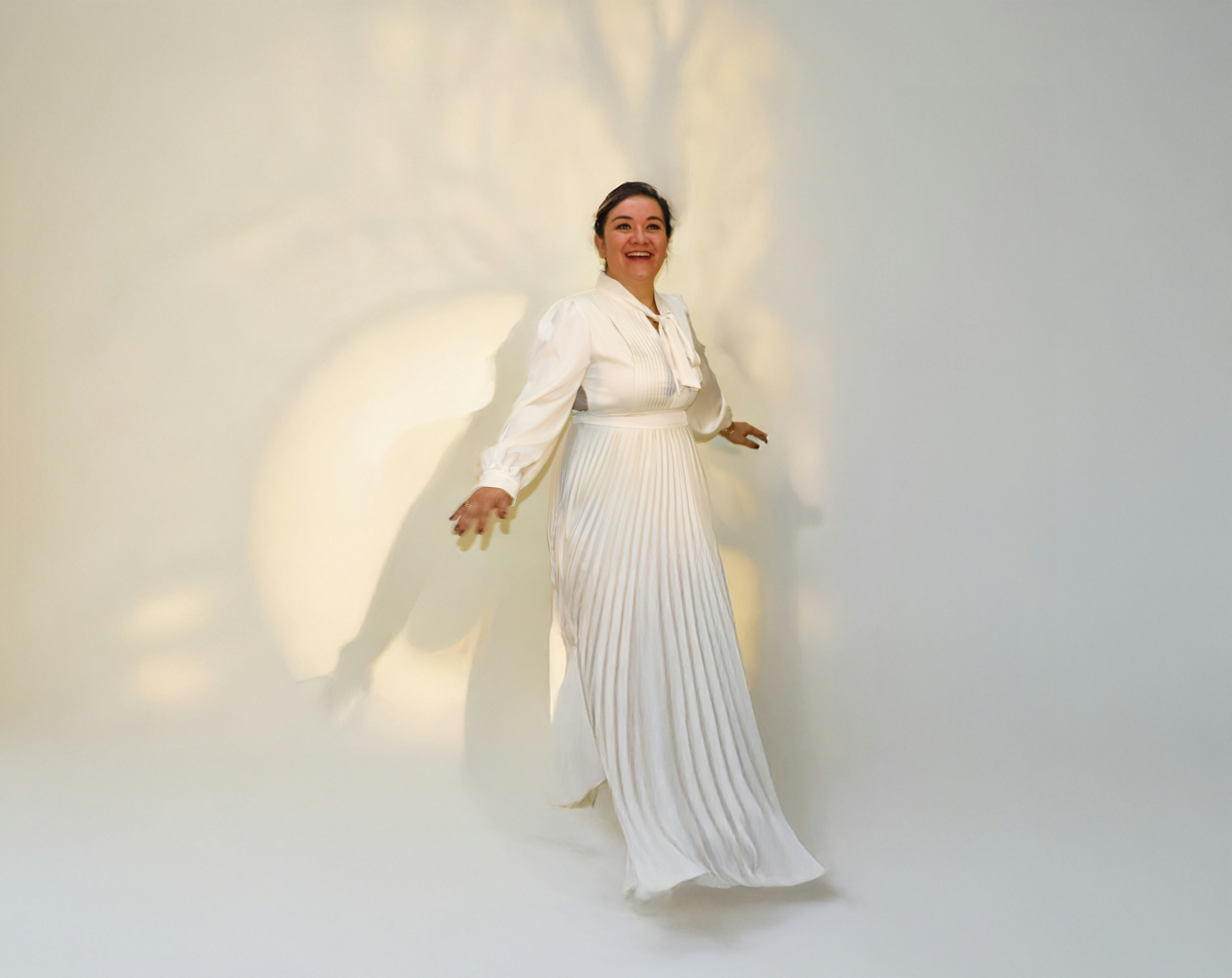 Frau in elegantem weißen Kleid mit plissiertem Rock