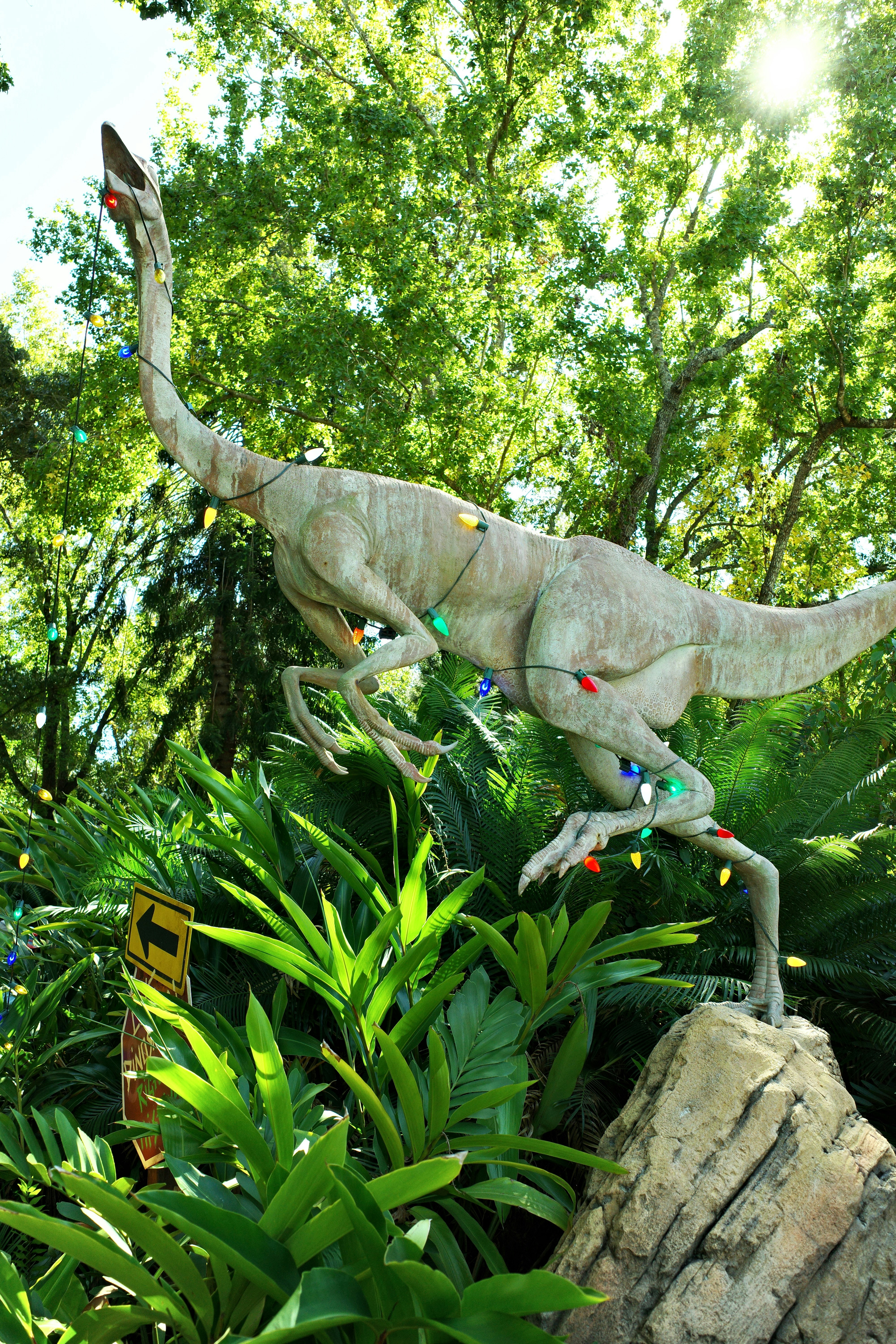 Statua di dinosauro decorata con luci colorate in un verde rigoglioso