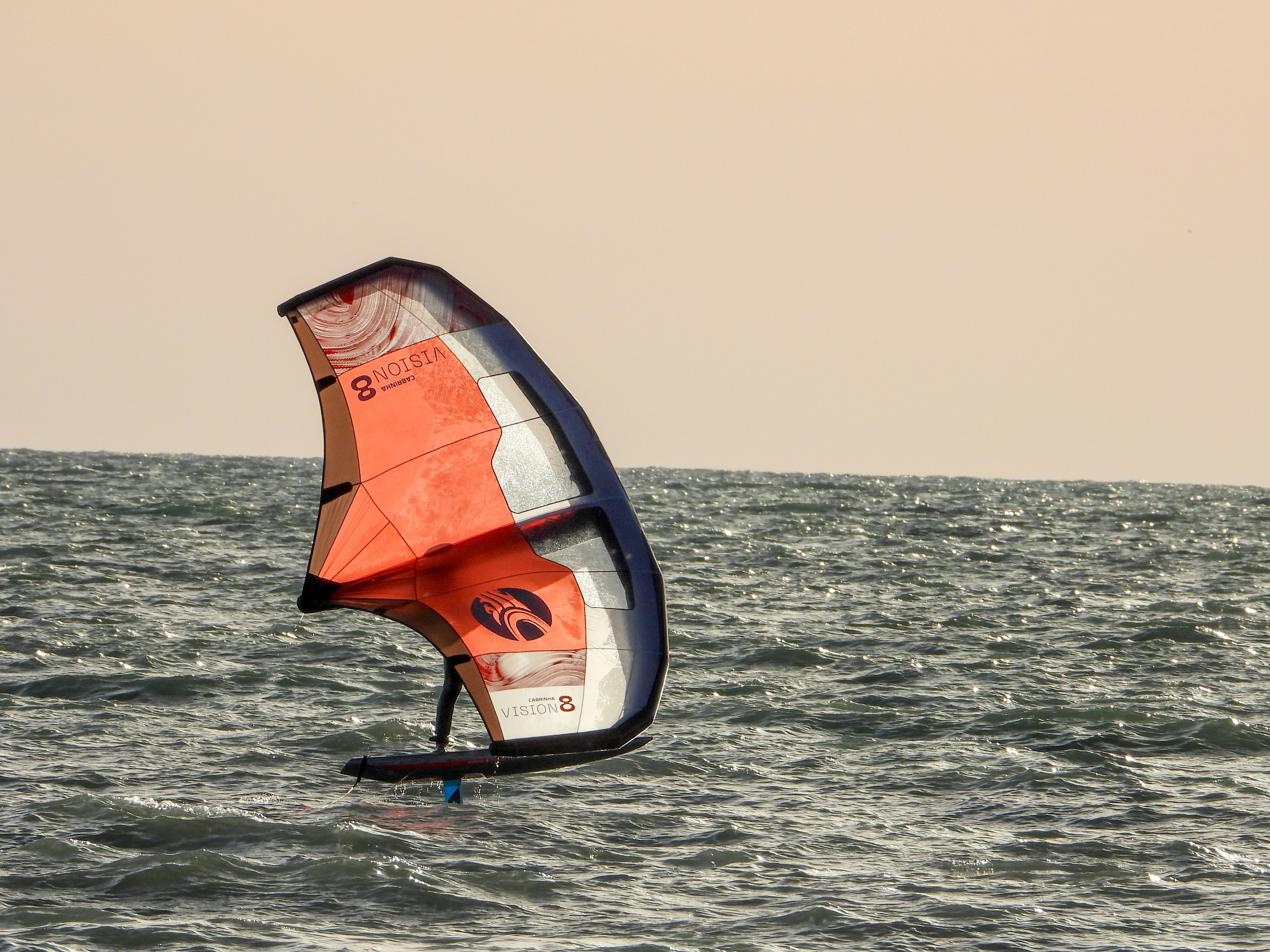 Person wing foiling on a choppy ocean