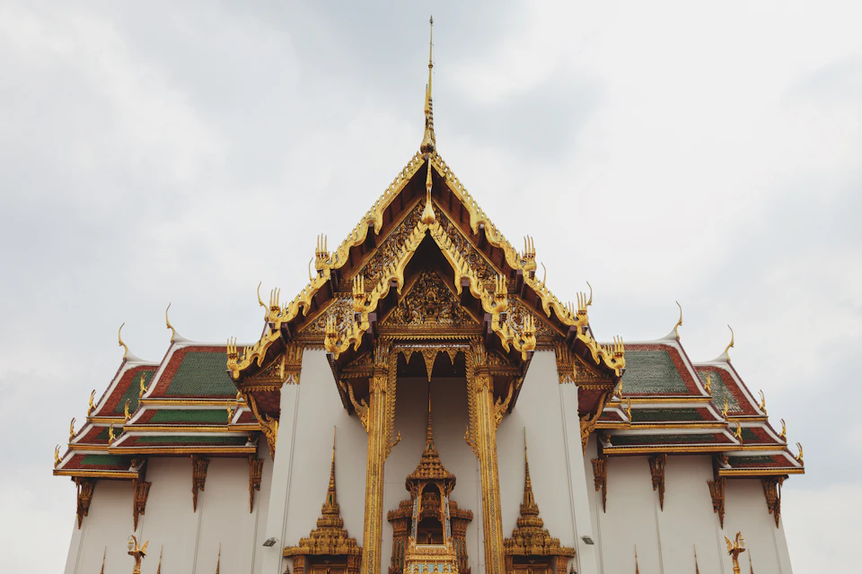 Large white temple complex with gold roof and intricate carvings dominates the landscape