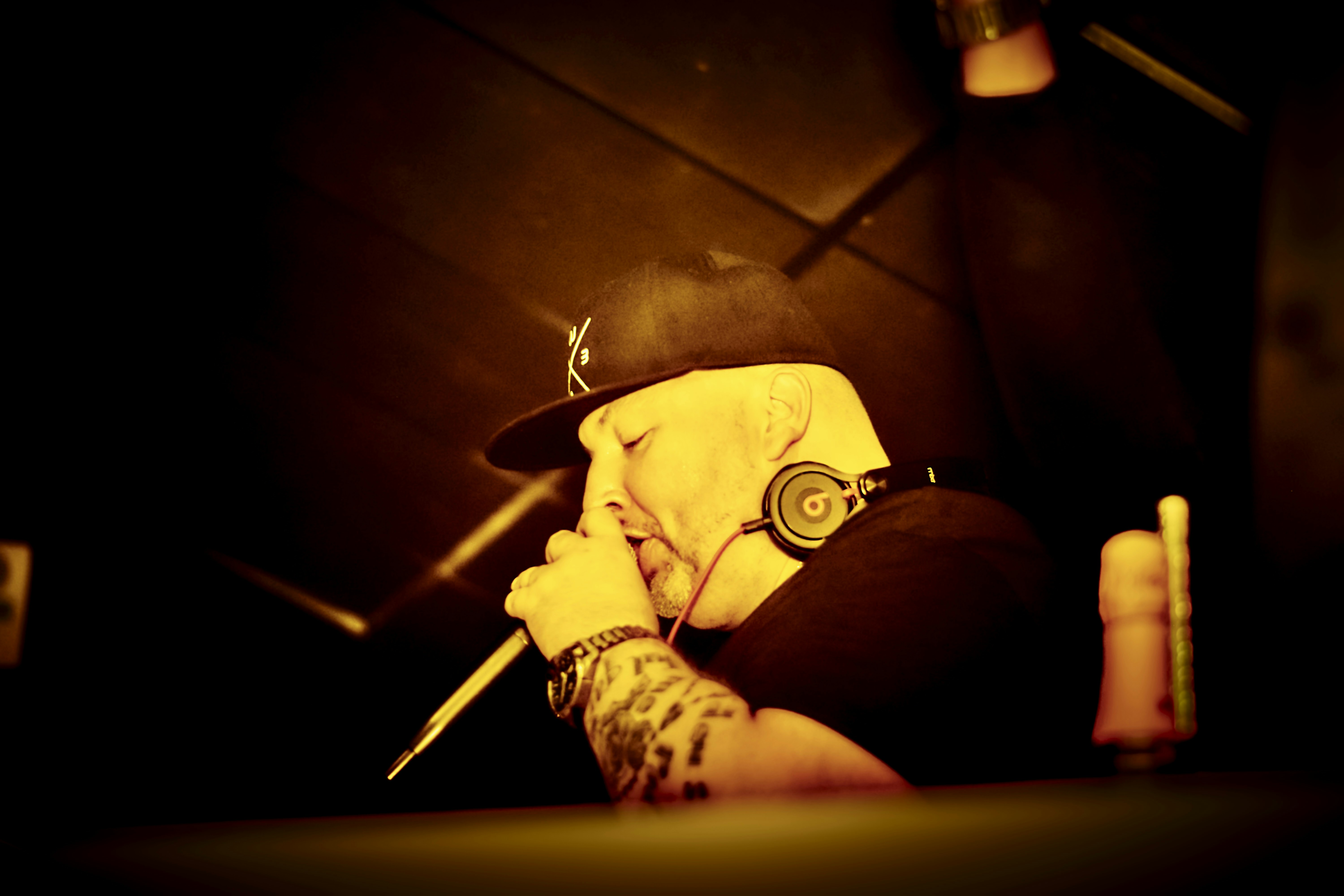 DJ wearing headphones and hat performing with a microphone