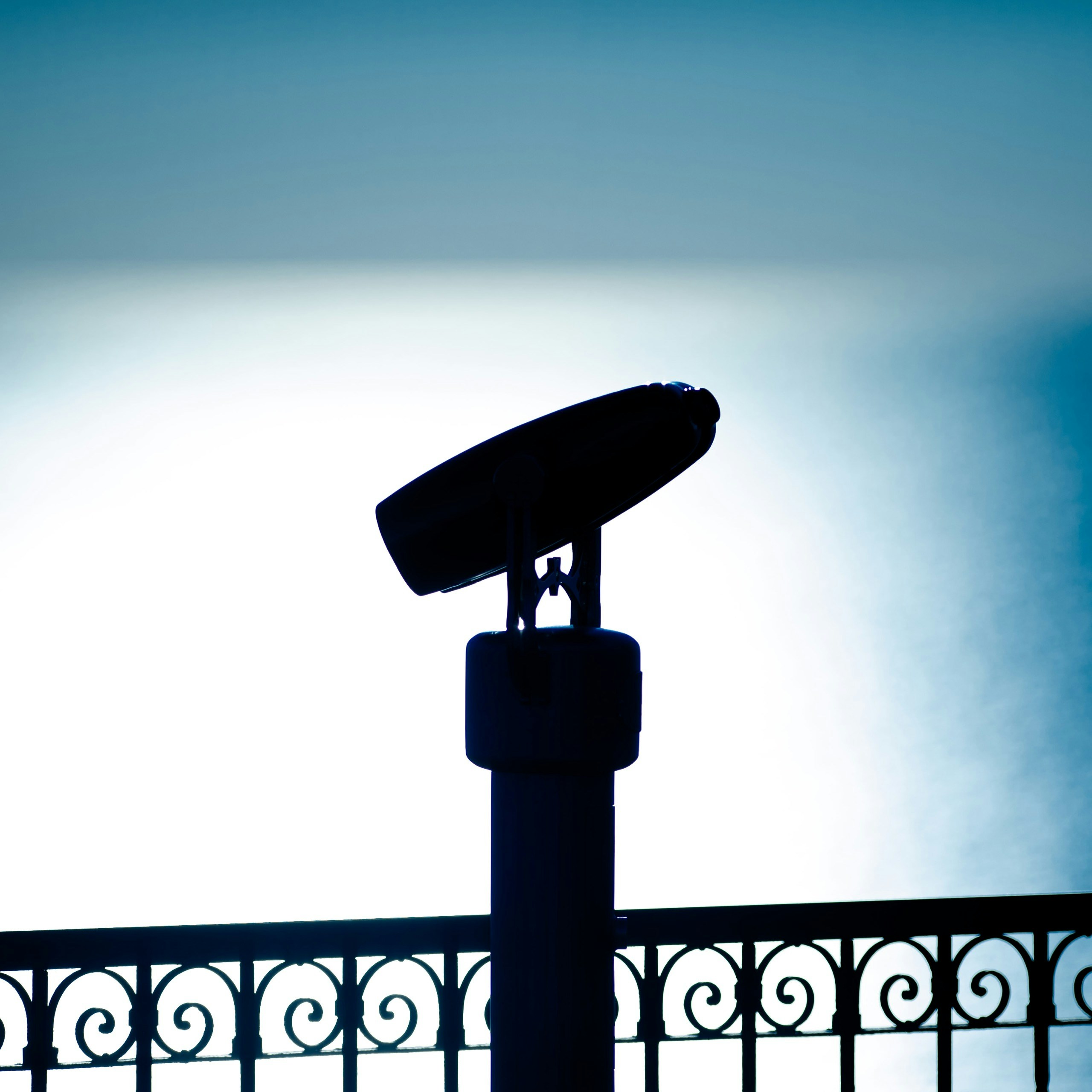 Silhouette of a telescope against a bright sky.