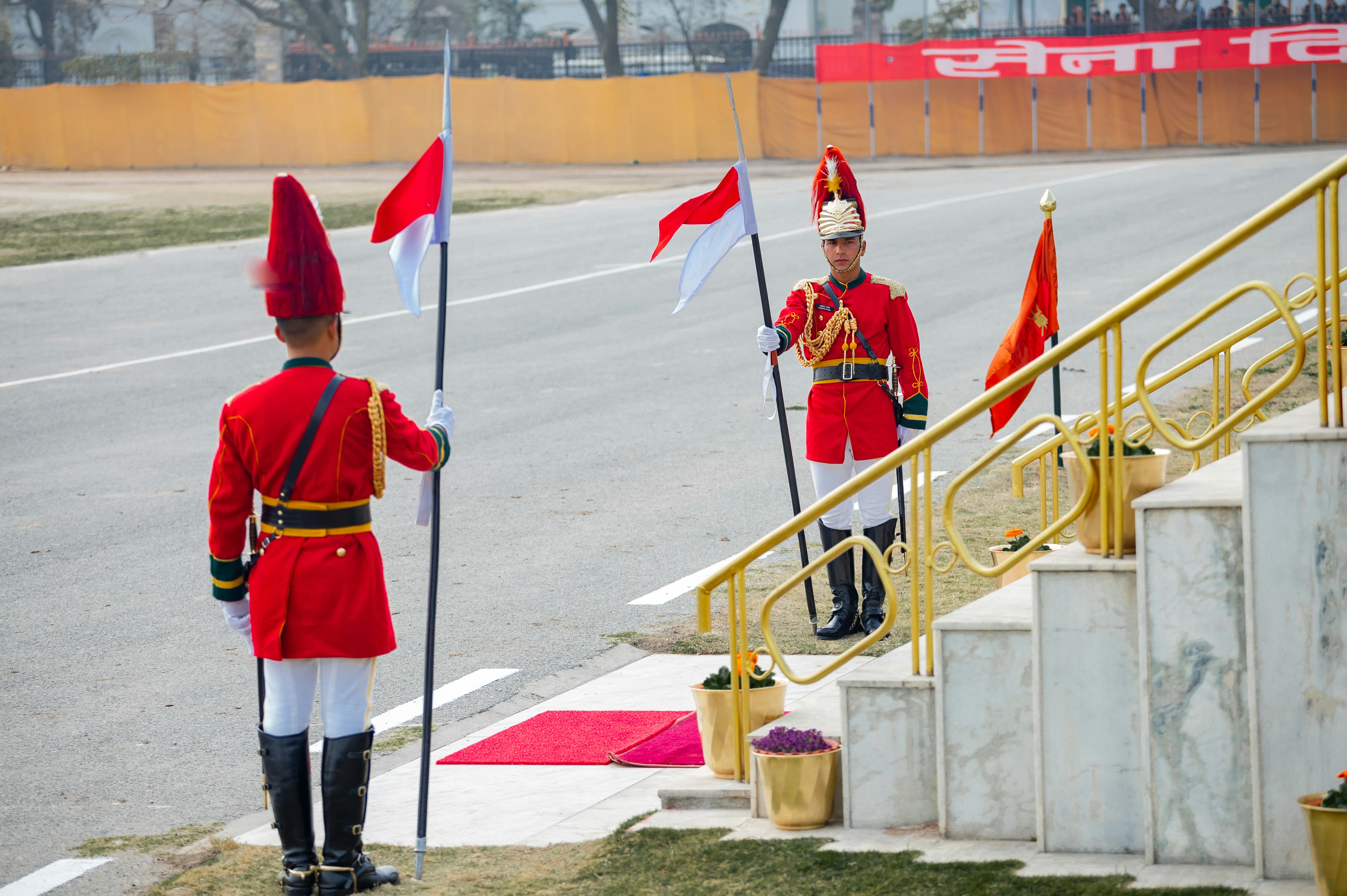 Two guards in red uniforms holding flags