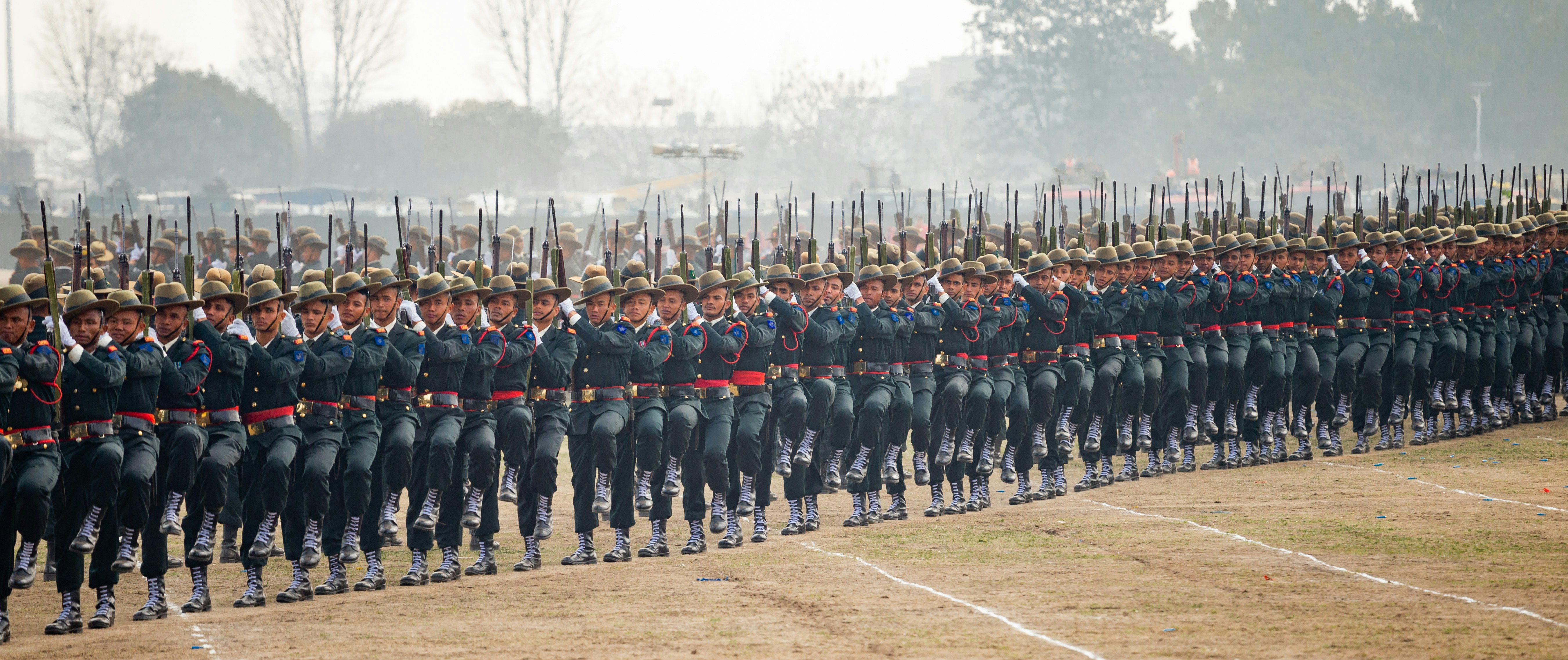 Soldiers in uniform marching in formation with rifles.