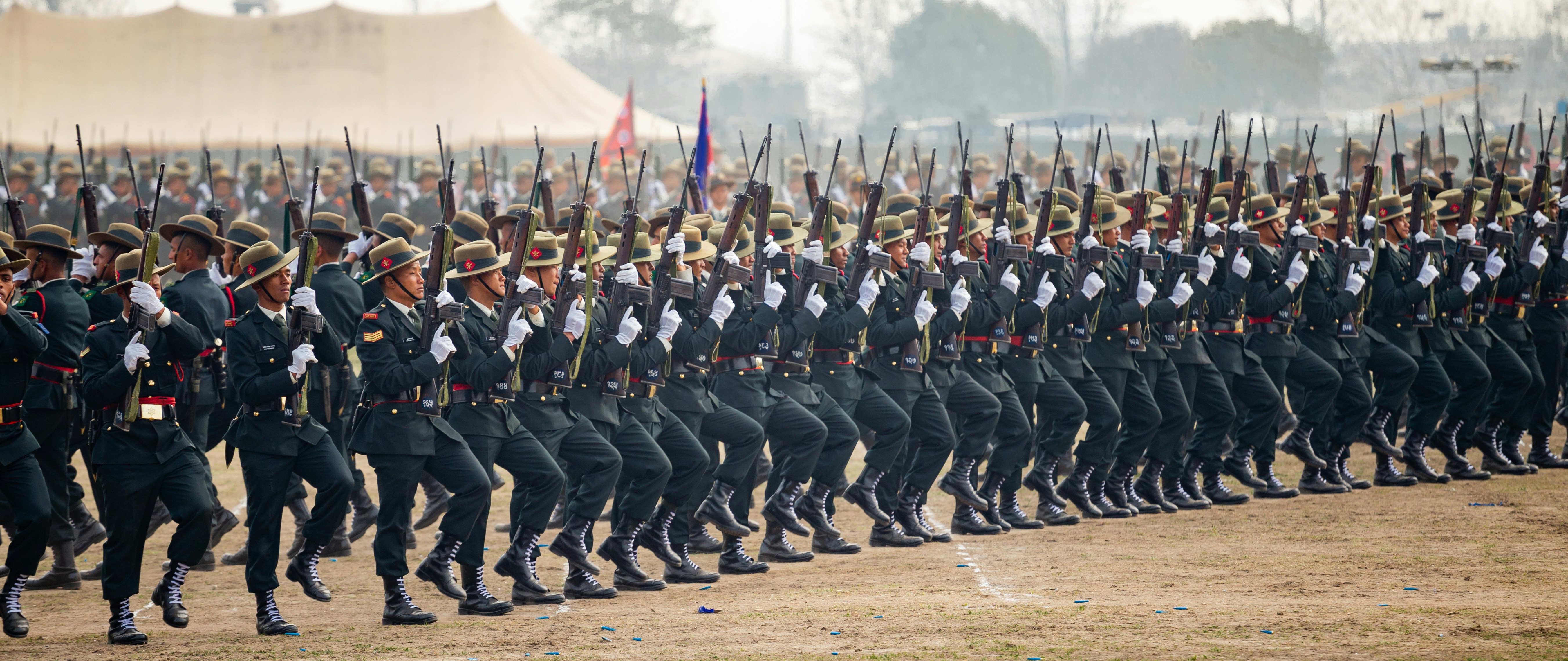 Soldiers in uniform marching in formation with rifles.