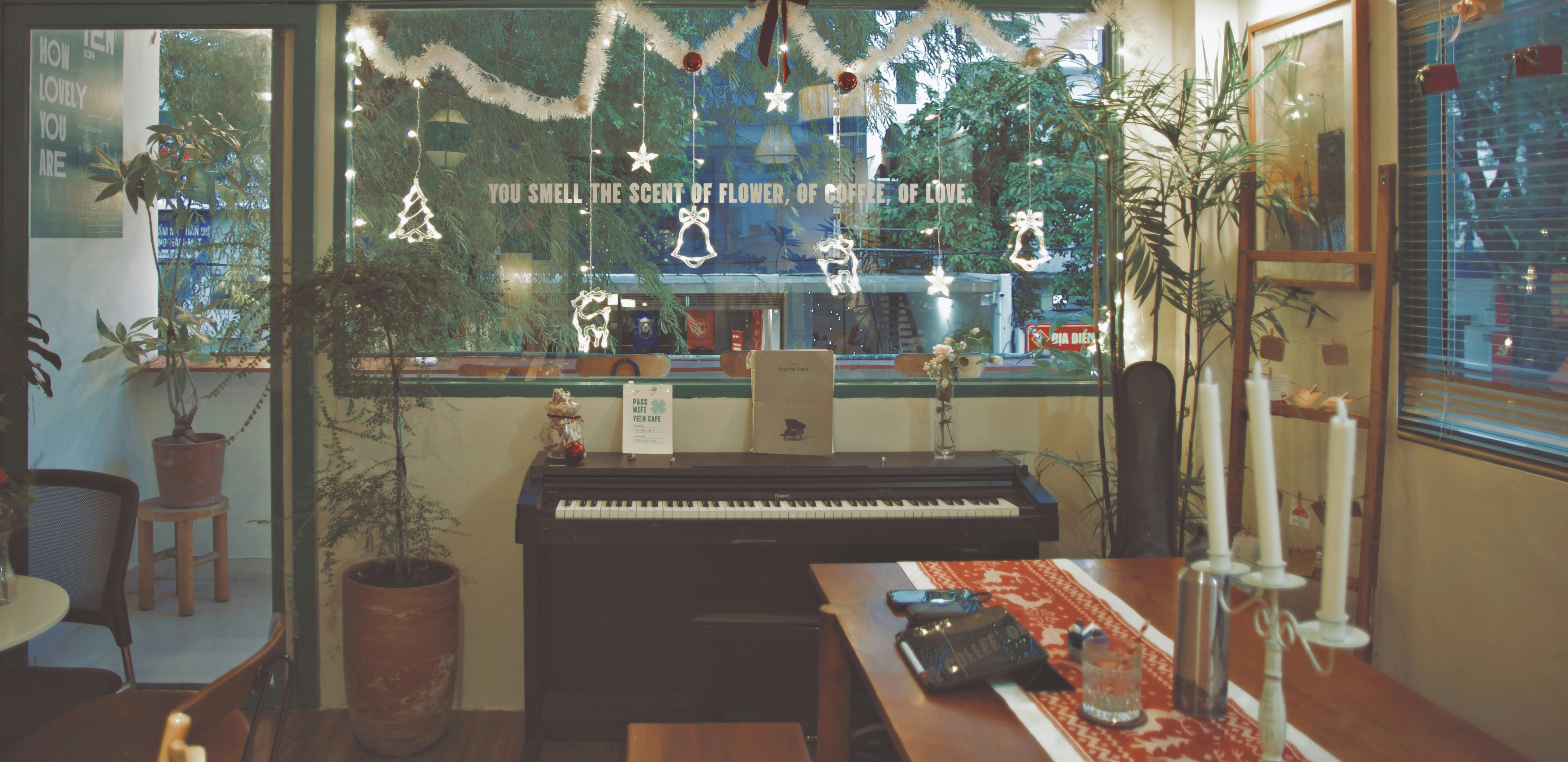 Piano decorated for christmas near a table with candles.