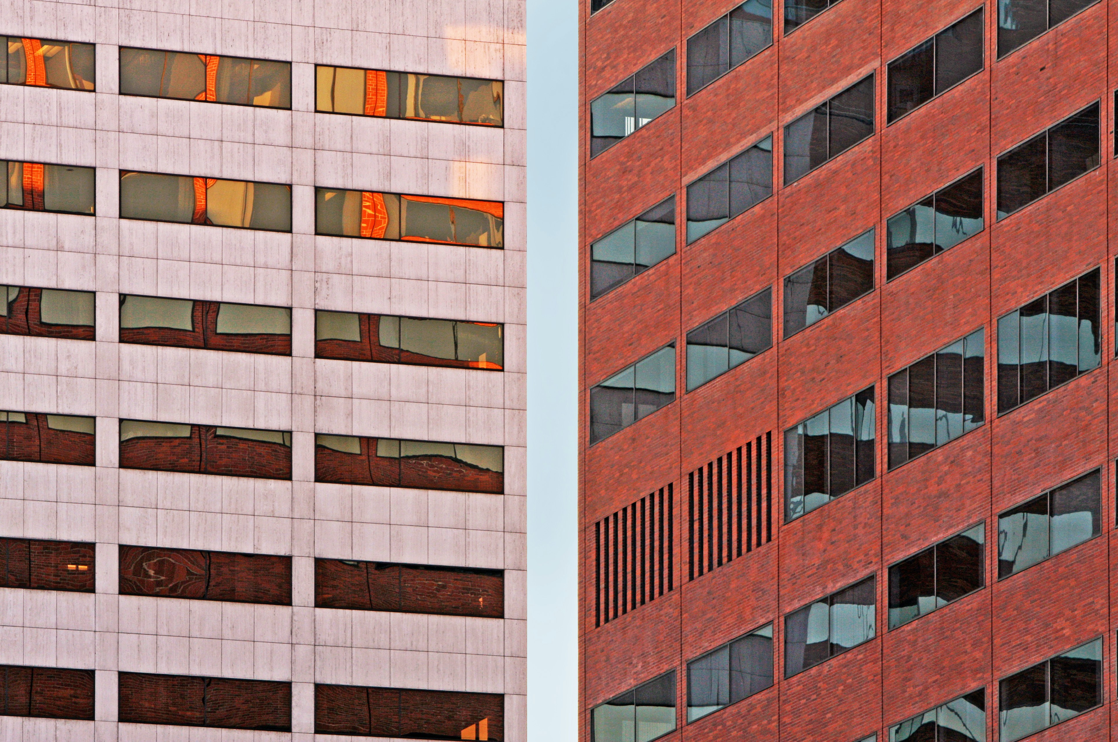 Two modern buildings with reflective windows against sky