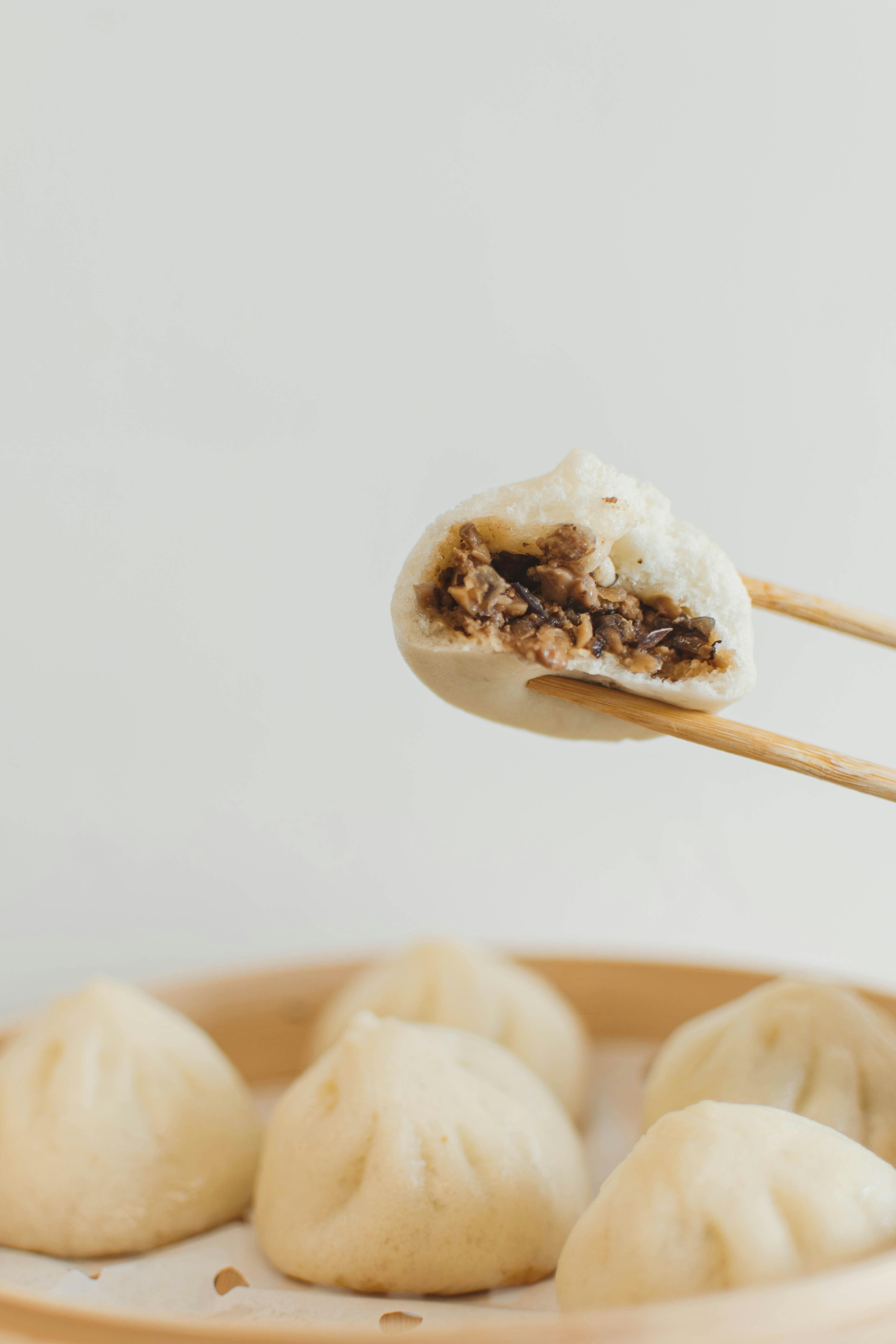 Steamed buns filled with meat held by chopsticks