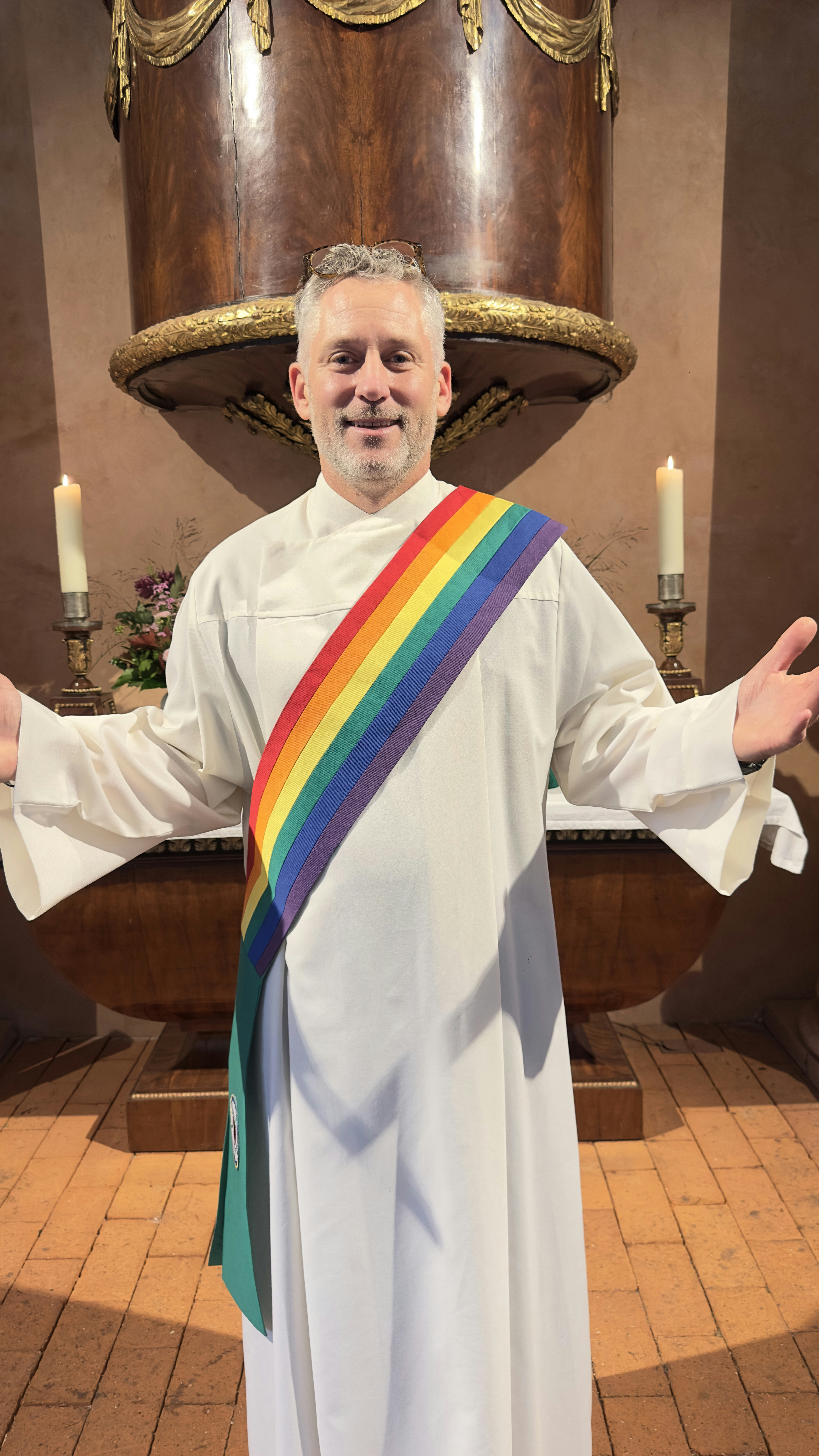 Clergy member wearing a rainbow stole in a church.