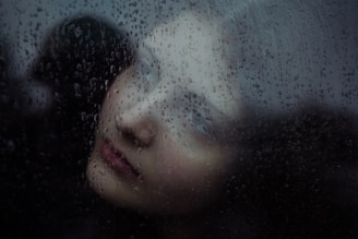 Woman's face seen through rain-streaked glass