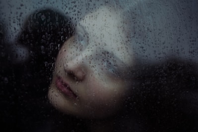 Woman's face seen through rain-streaked glass
