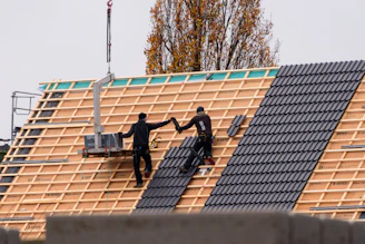 Workers installing roof tiles on a new building.
