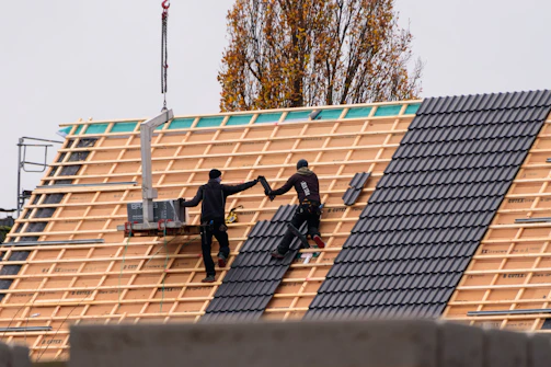 Workers installing roof tiles on a new building.