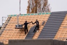 Workers installing roof tiles on a new building.