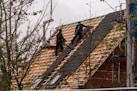 Workers installing shingles on a steep roof
