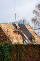 Workers installing roofing tiles on a house under-construction house.