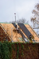 Workers installing roofing tiles on a house under-construction house.