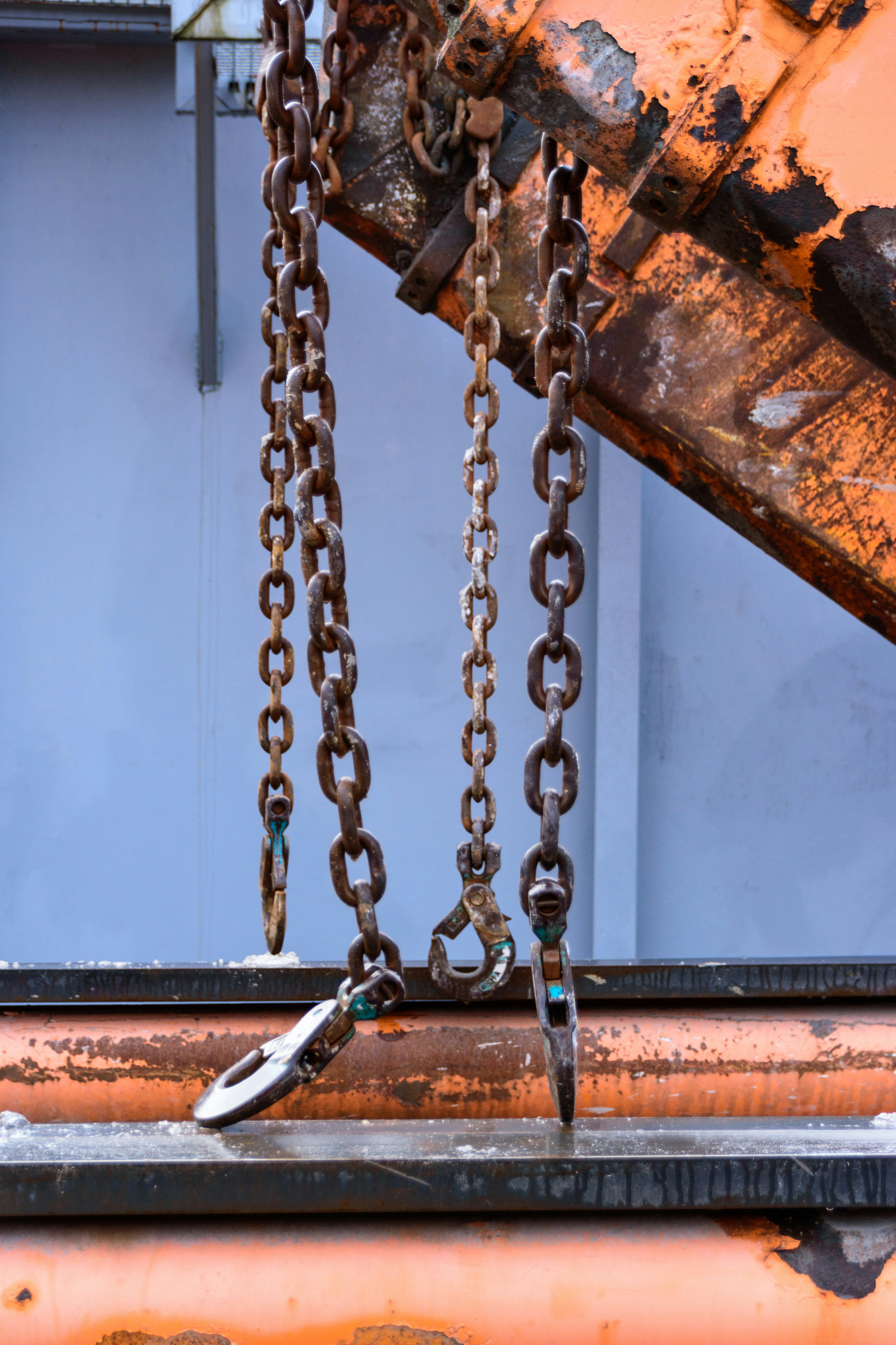 Mehrere rostige Metallketten, die von Maschinen hingen.