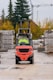 Red forklift driving on a wet construction site.