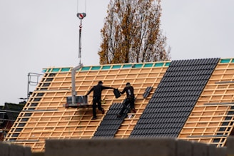 Construction workers installing roof tiles on a new building.