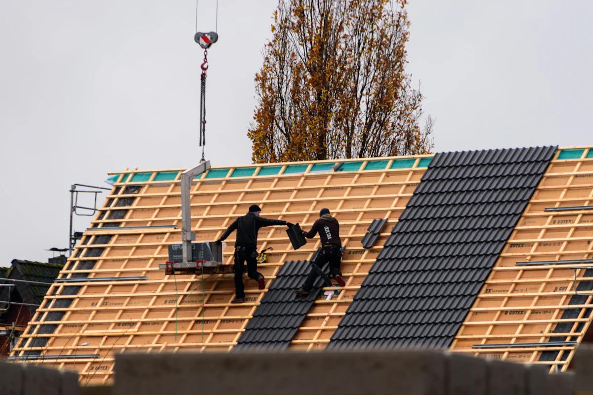 Roofers installing clay tiles on a new build