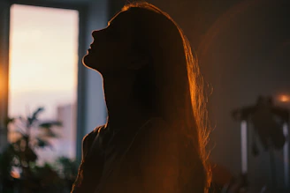 Silhouette of a woman looking up at the sun.
