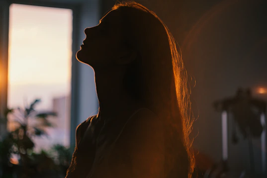 Silhouette of a woman looking up at the sun.