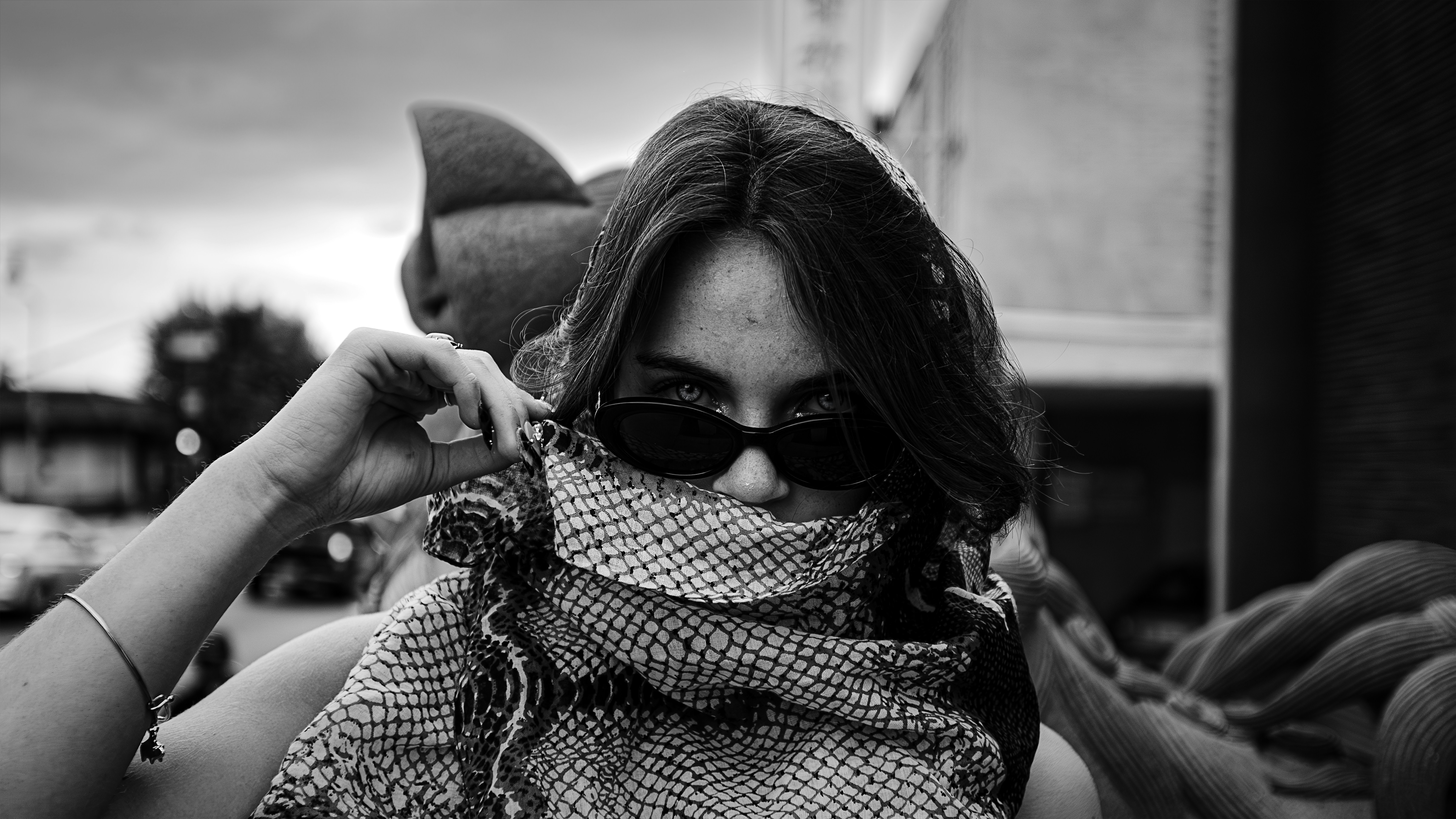 Woman wearing scarf and sunglasses, looking at camera
