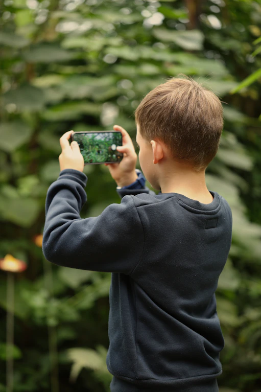 Boy taking a picture of plants with smartphone