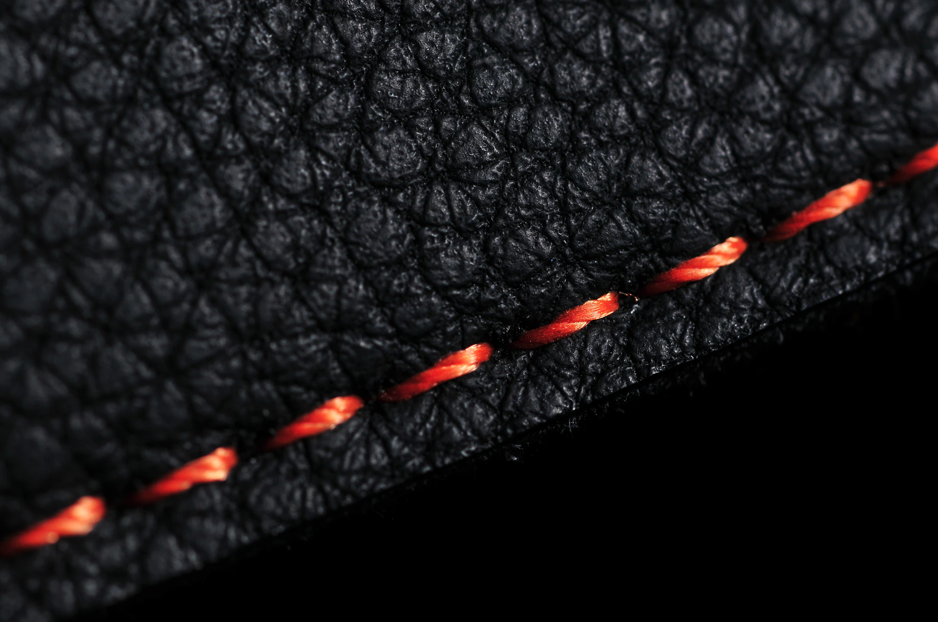 Close-up of black leather with orange stitching