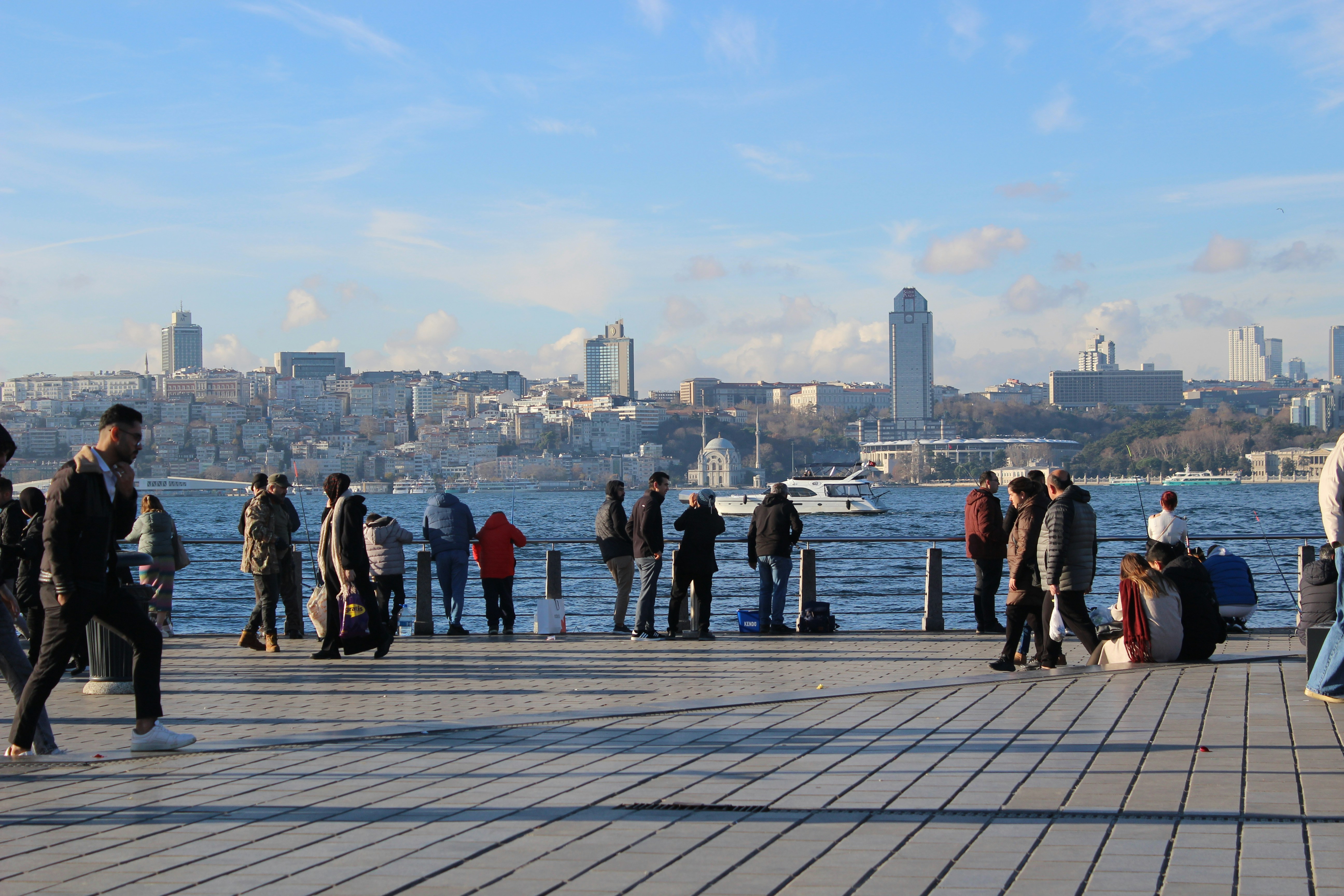 People walking along a waterfront with city skyline