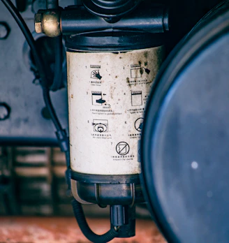 Close-up of a dirty fuel filter on a vehicle.