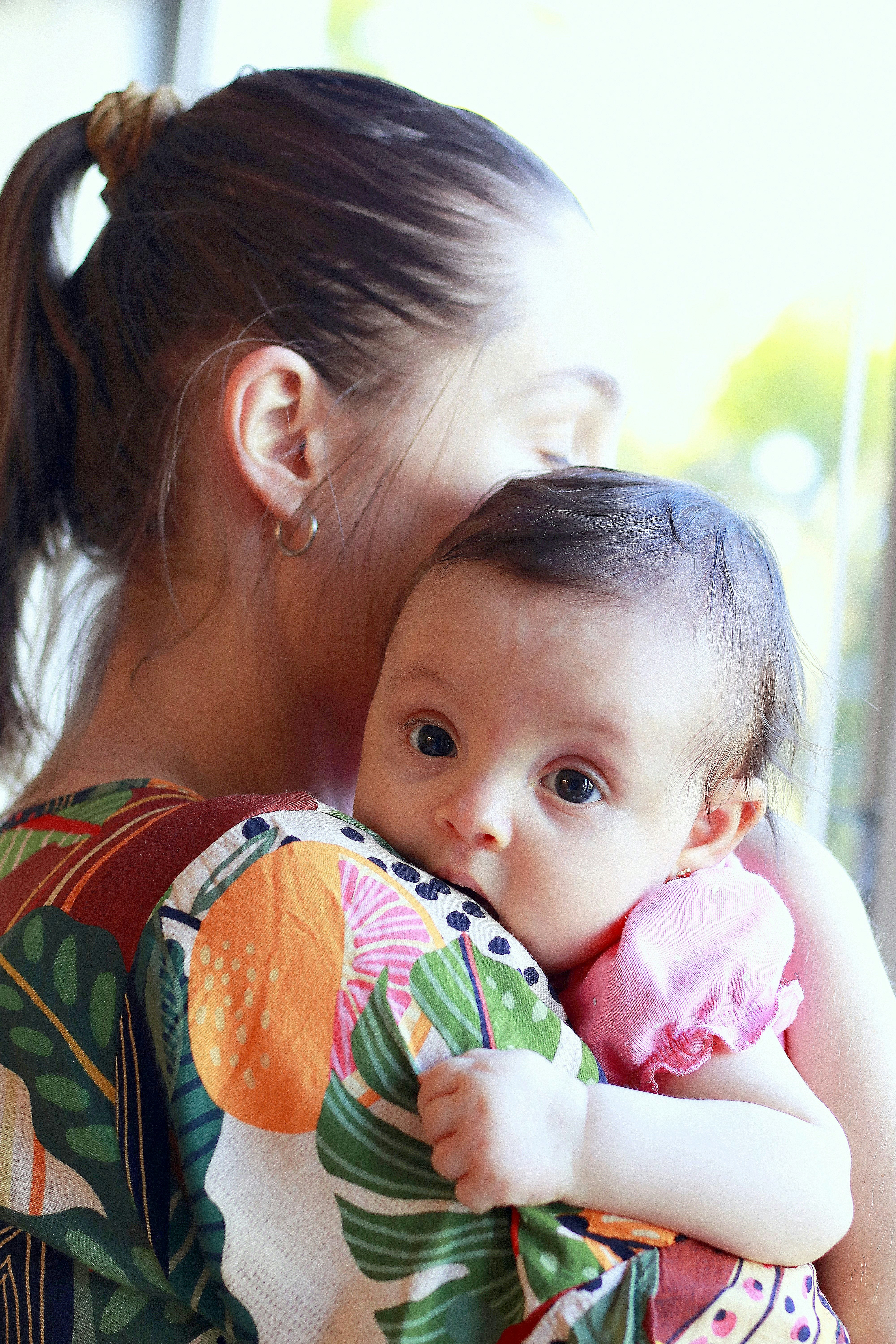 A mother holds her baby close to her chest.