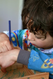 Young child focused on building with wooden blocks.