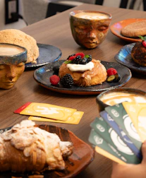 Pastries and coffee served with unique face-shaped mugs.