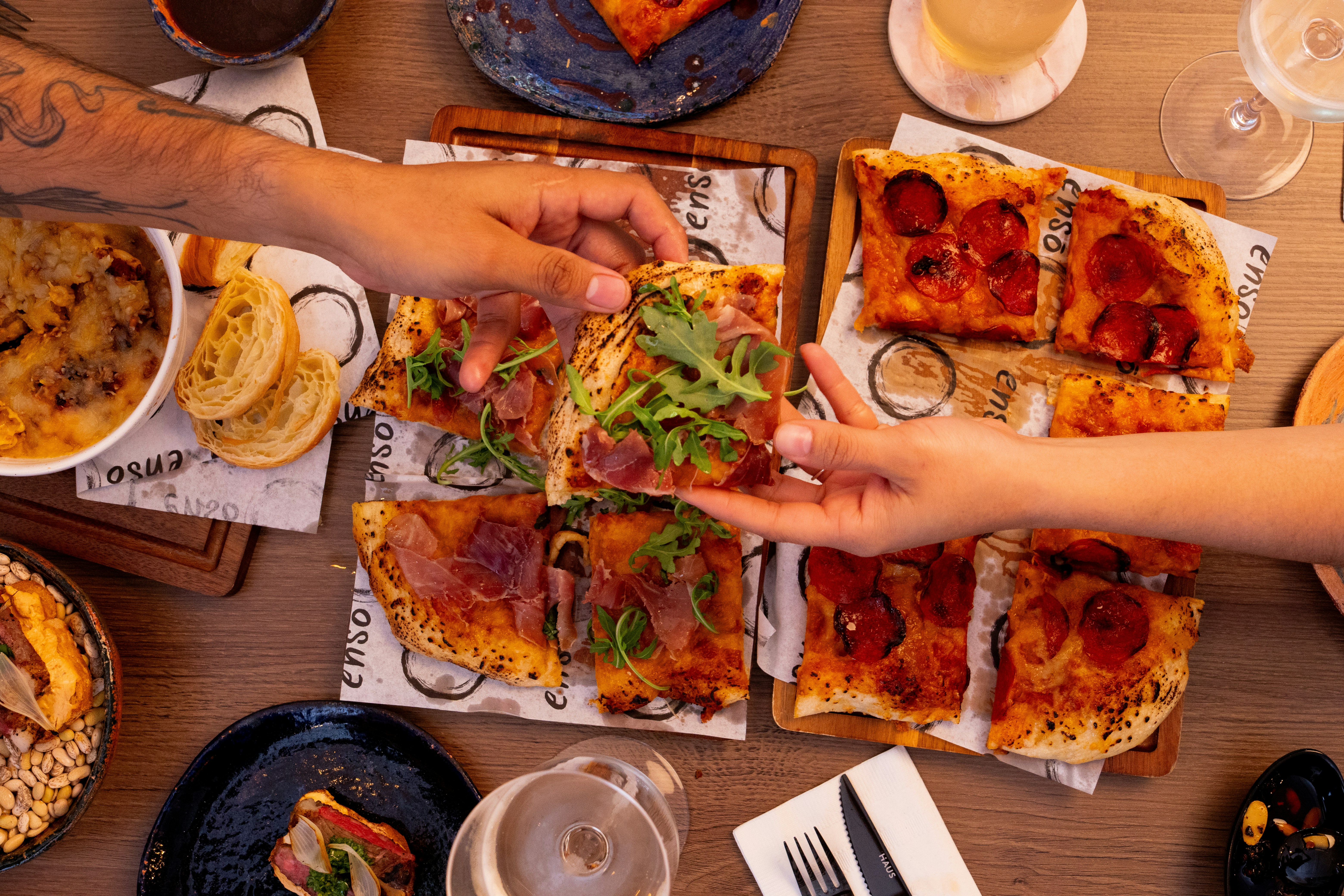 People sharing various pizzas and appetizers at a table.