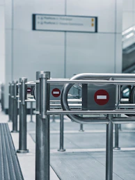 Metal turnstiles with red prohibition signs at station.