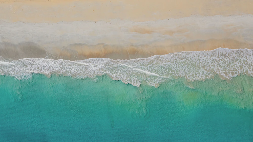 Turquoise water breaking on the sand a short walk from Driftwood House.