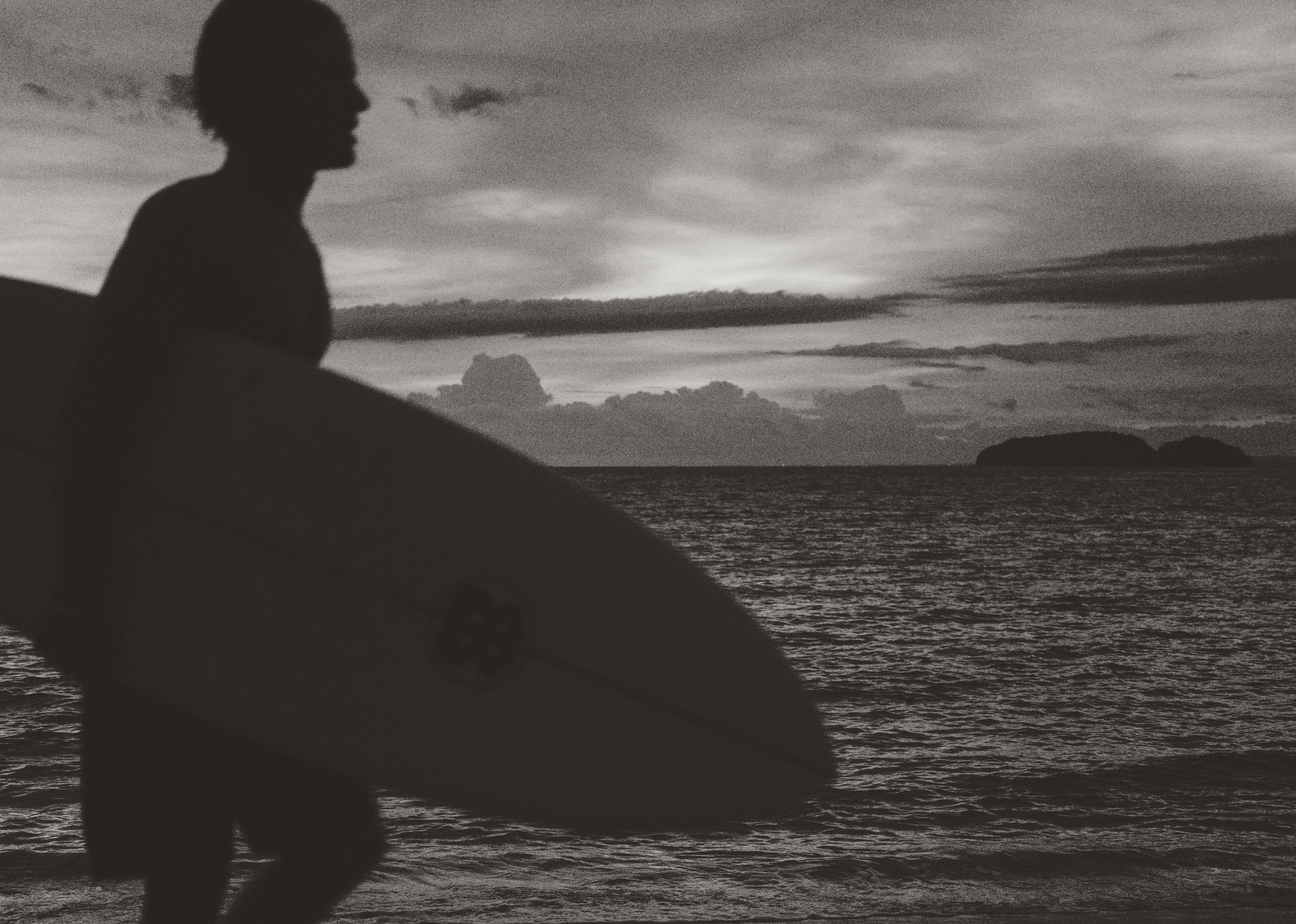 Surfer walking on beach at sunset