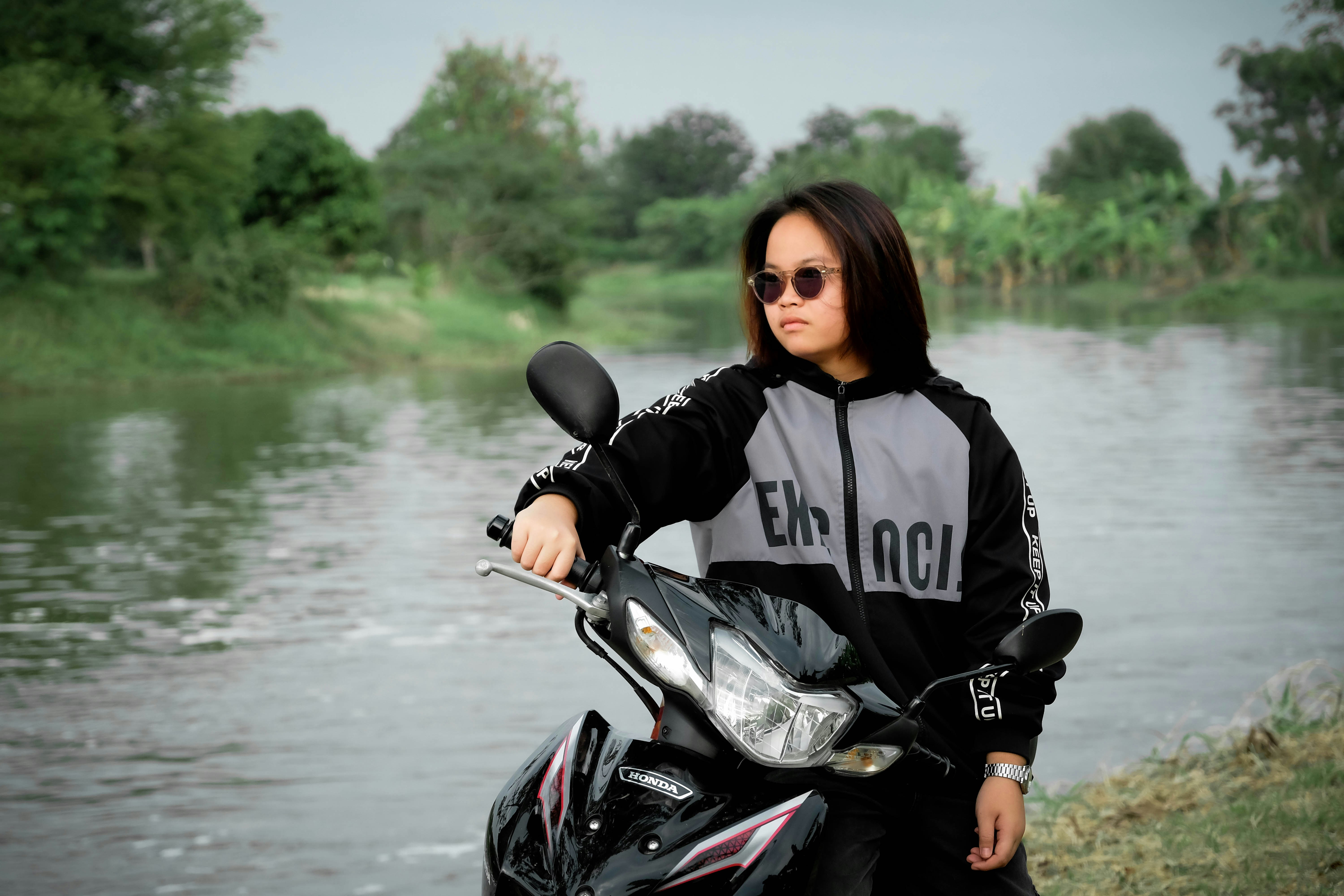 Joven con gafas de sol en una moto junto al río.