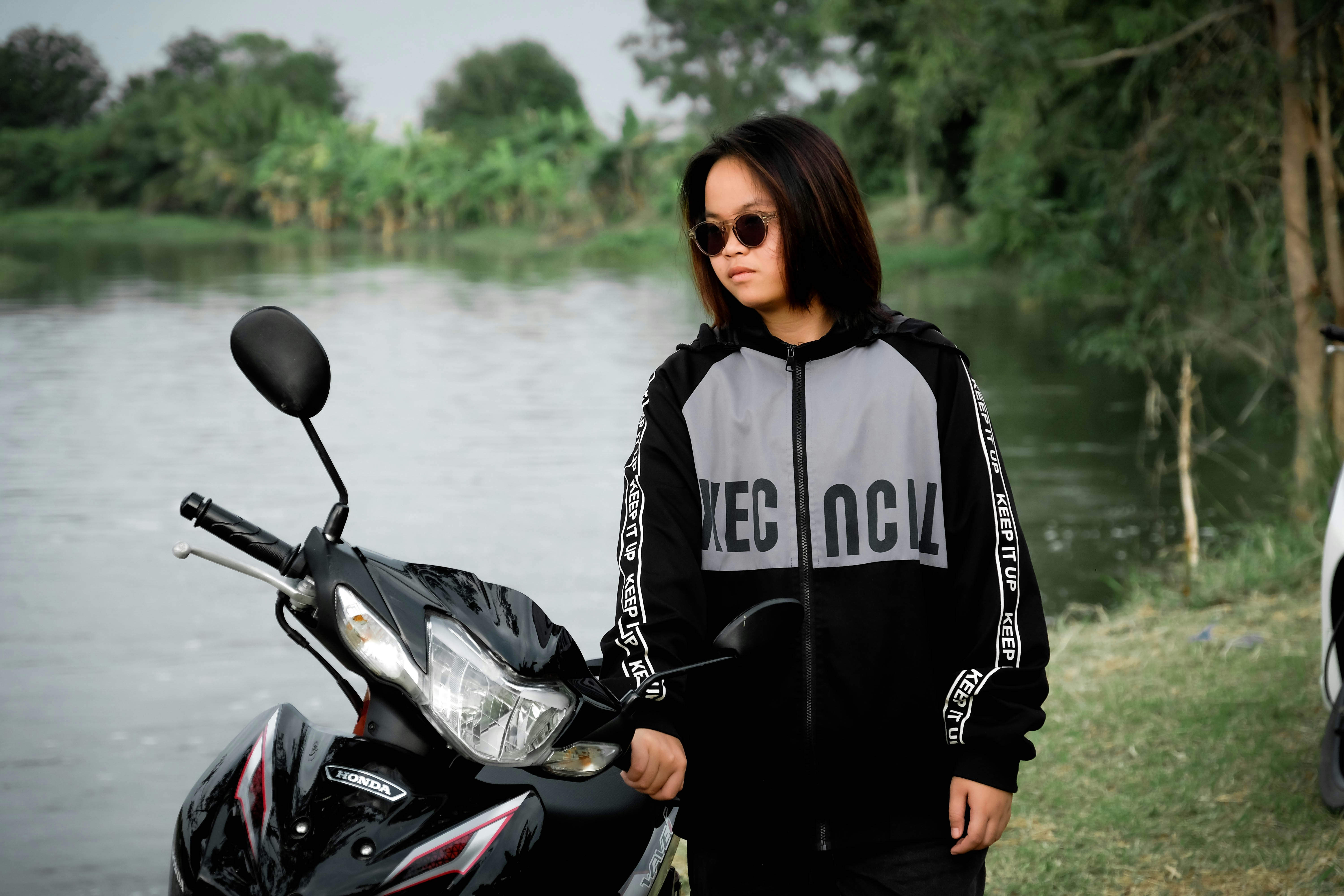 Joven con gafas de sol junto a una moto junto al agua