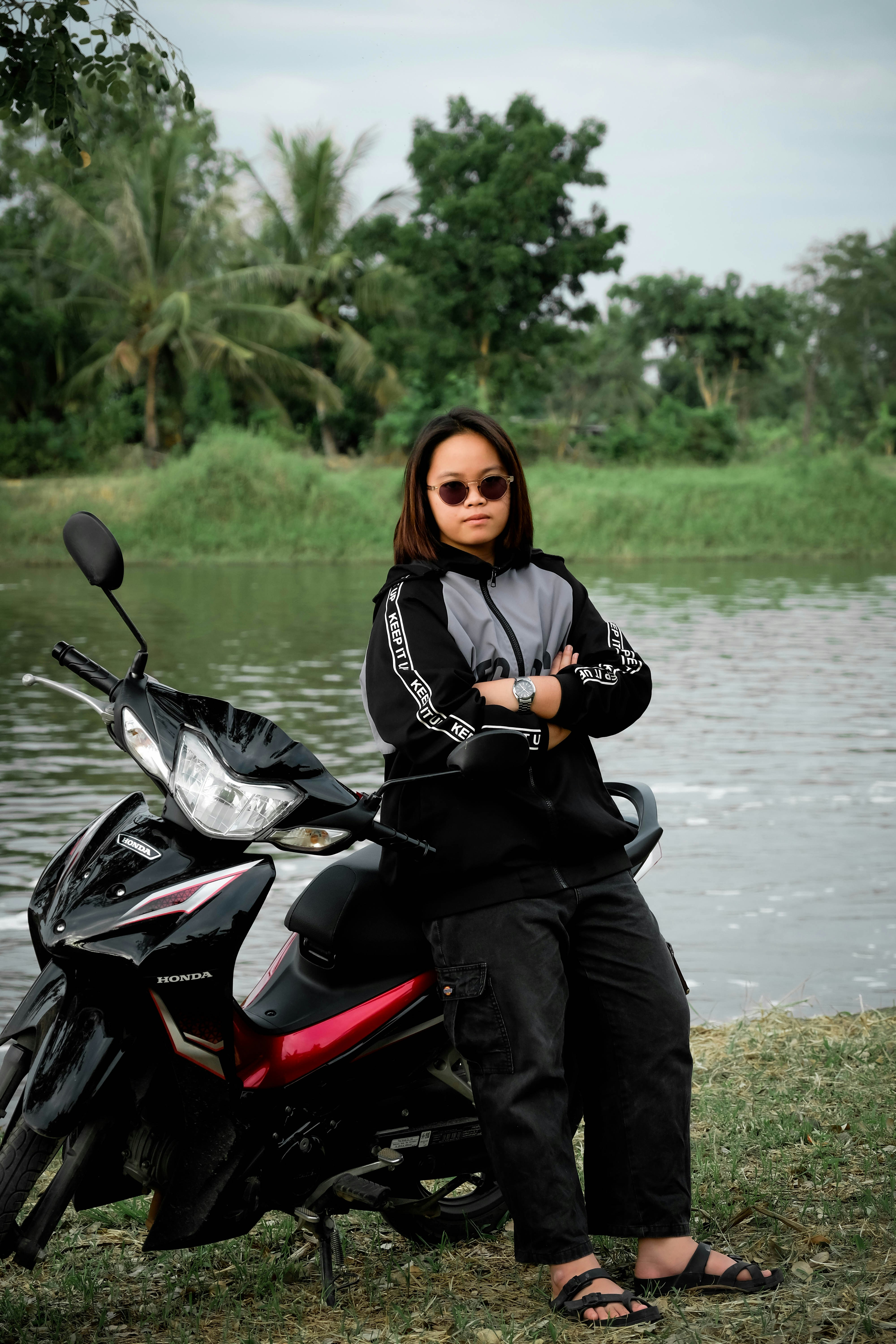 Mujer posando con una moto junto a un río