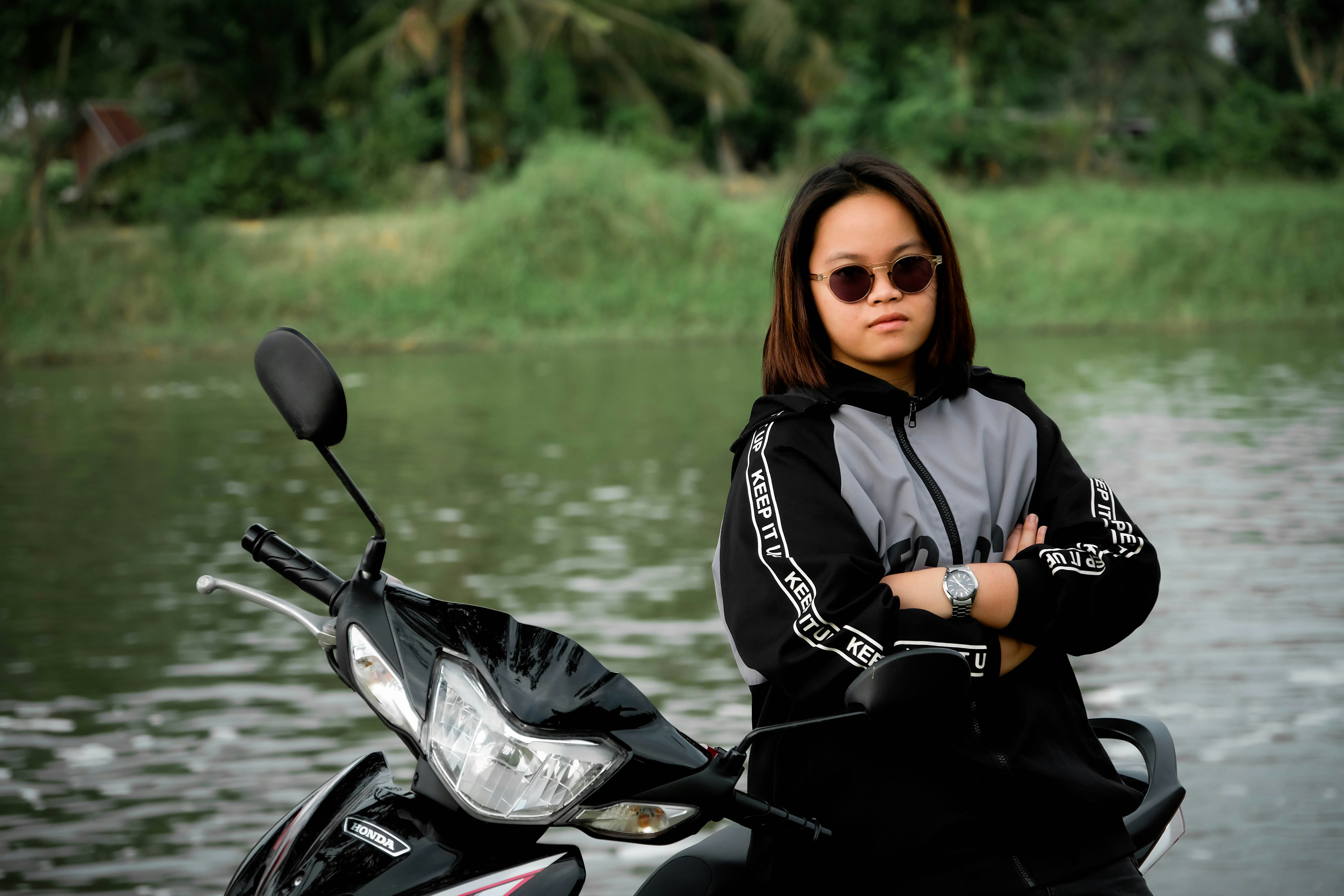 Joven con gafas de sol en un scooter junto al agua