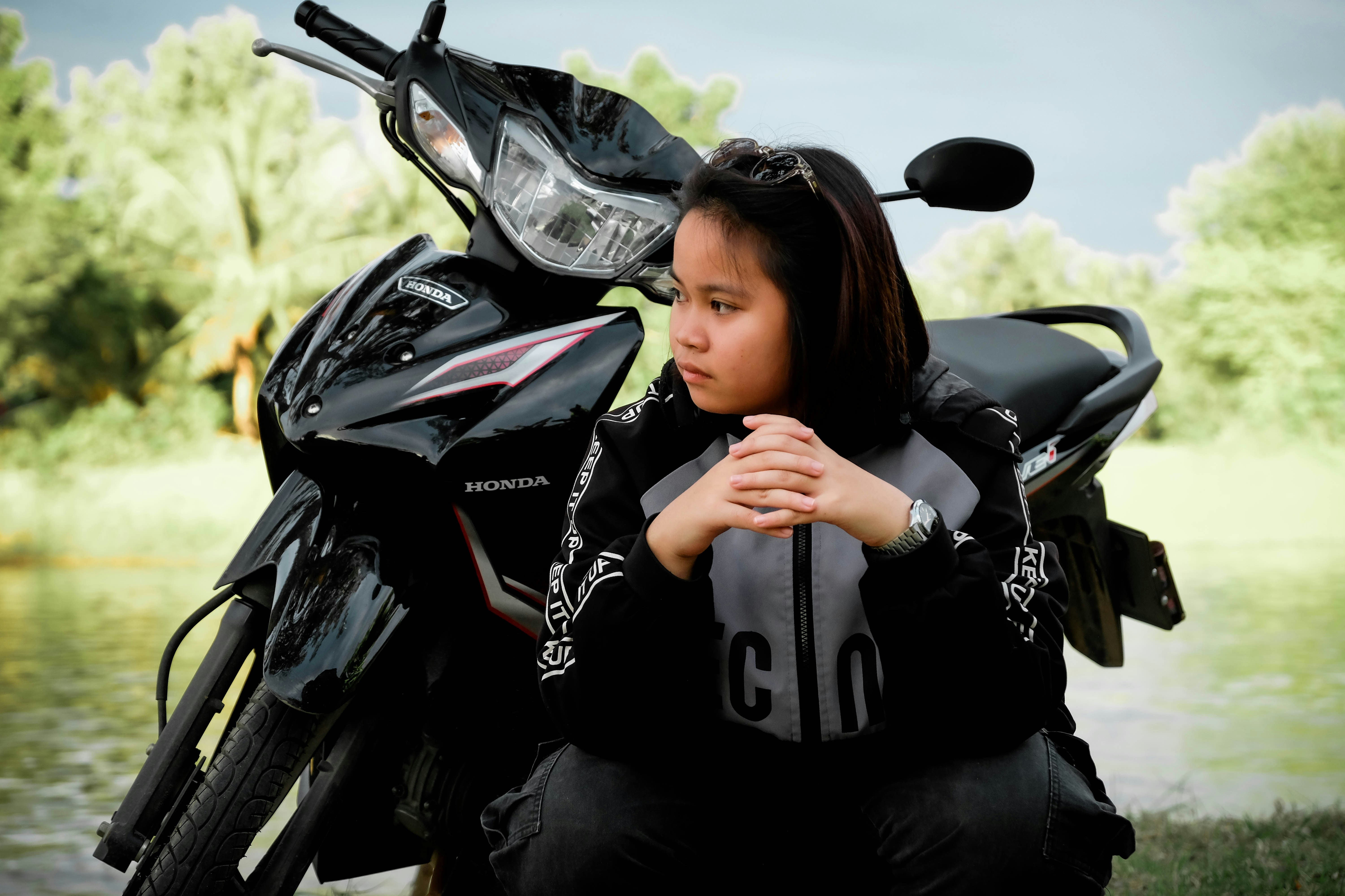 Una joven se sienta frente a una moto negra.