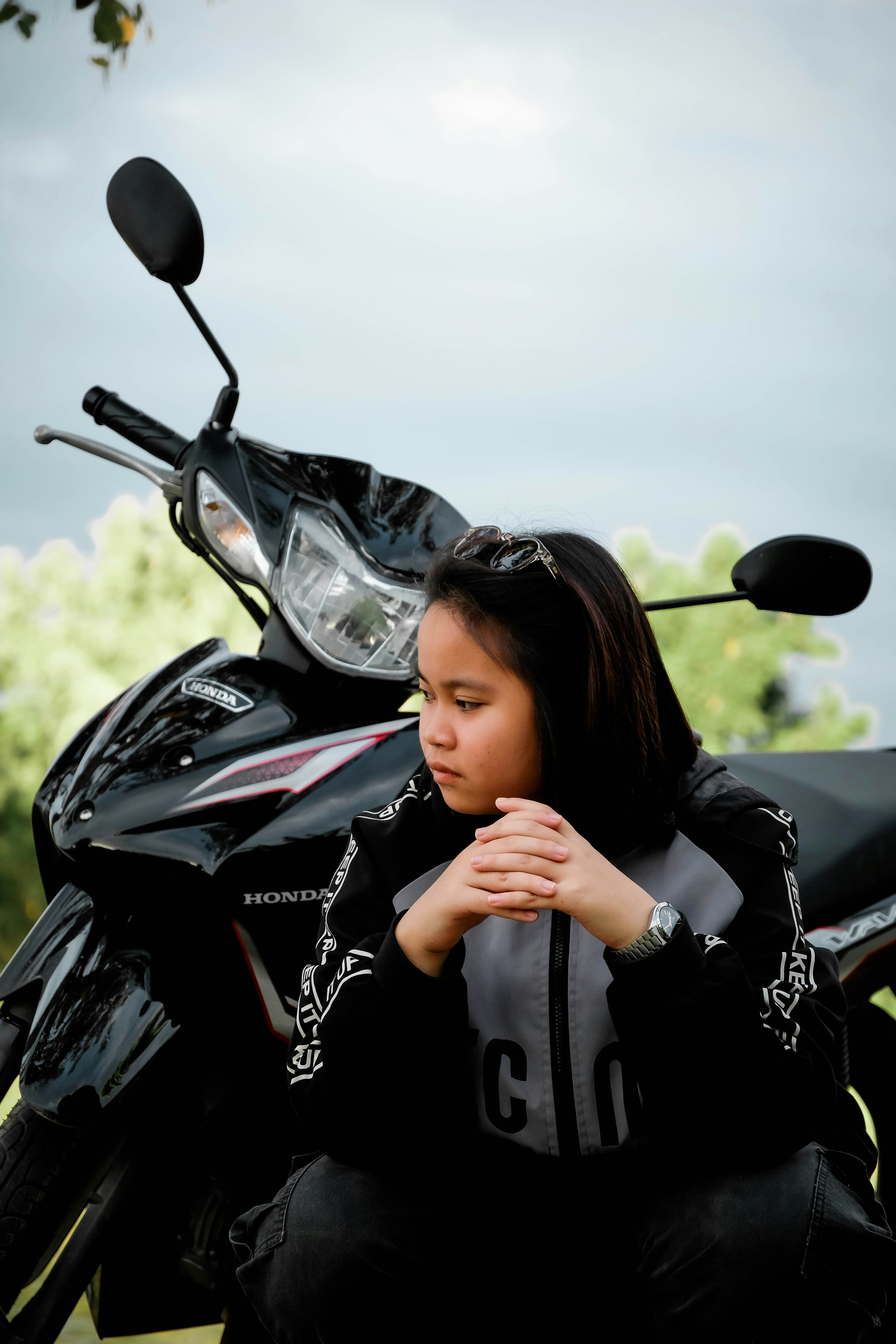 Una niña sentada junto a una moto.
