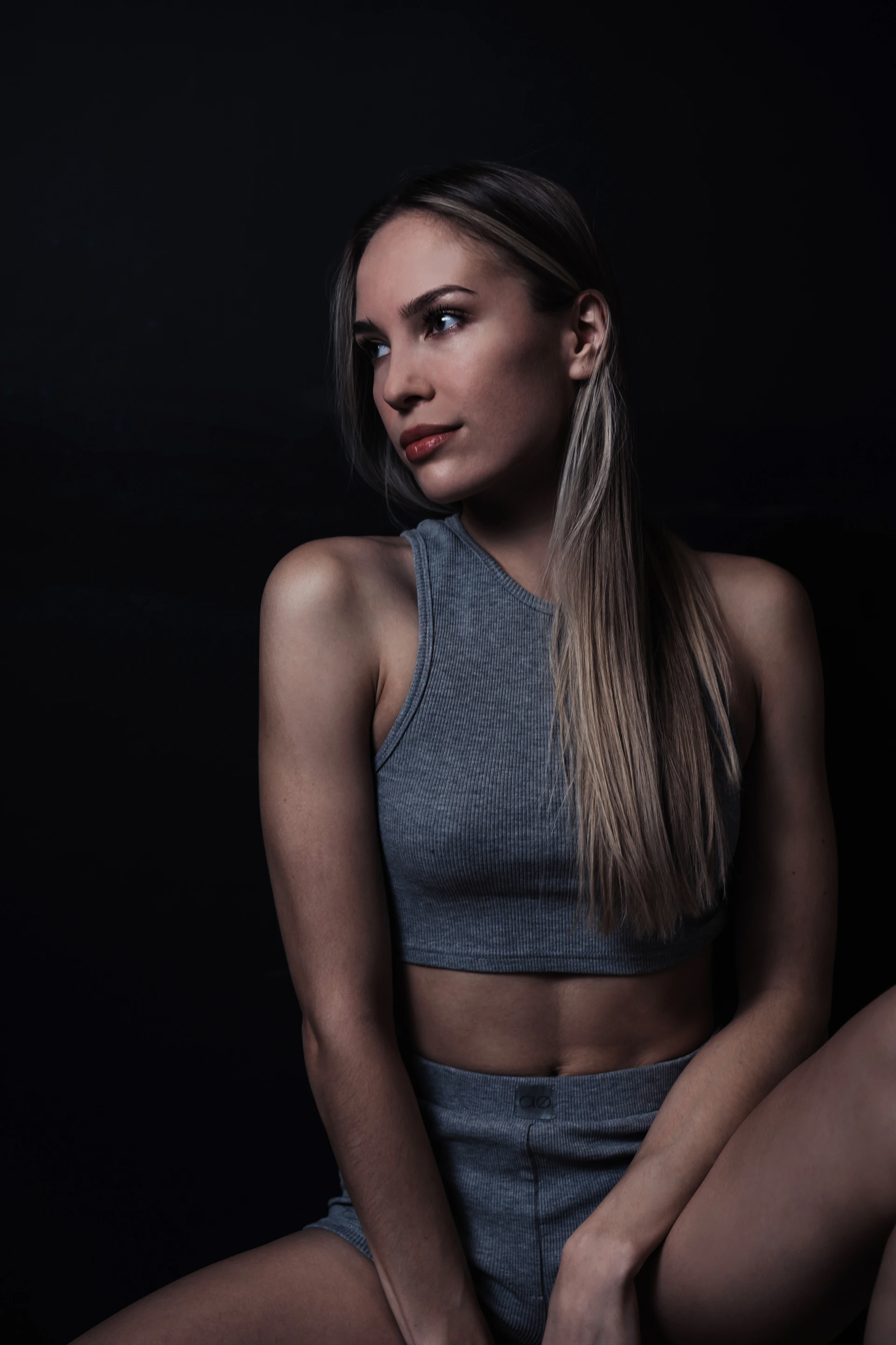 A woman in athletic wear against a dark background