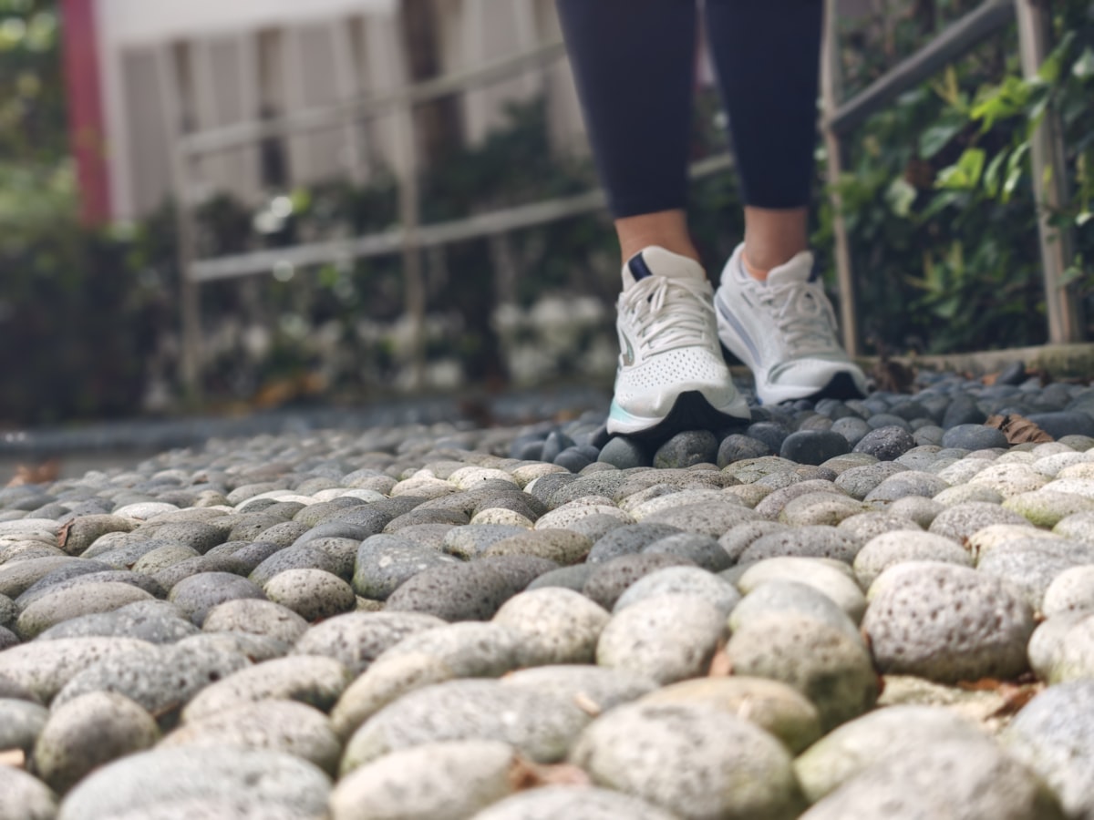 운동화를 신고 자갈길을 걷는 사람의 발